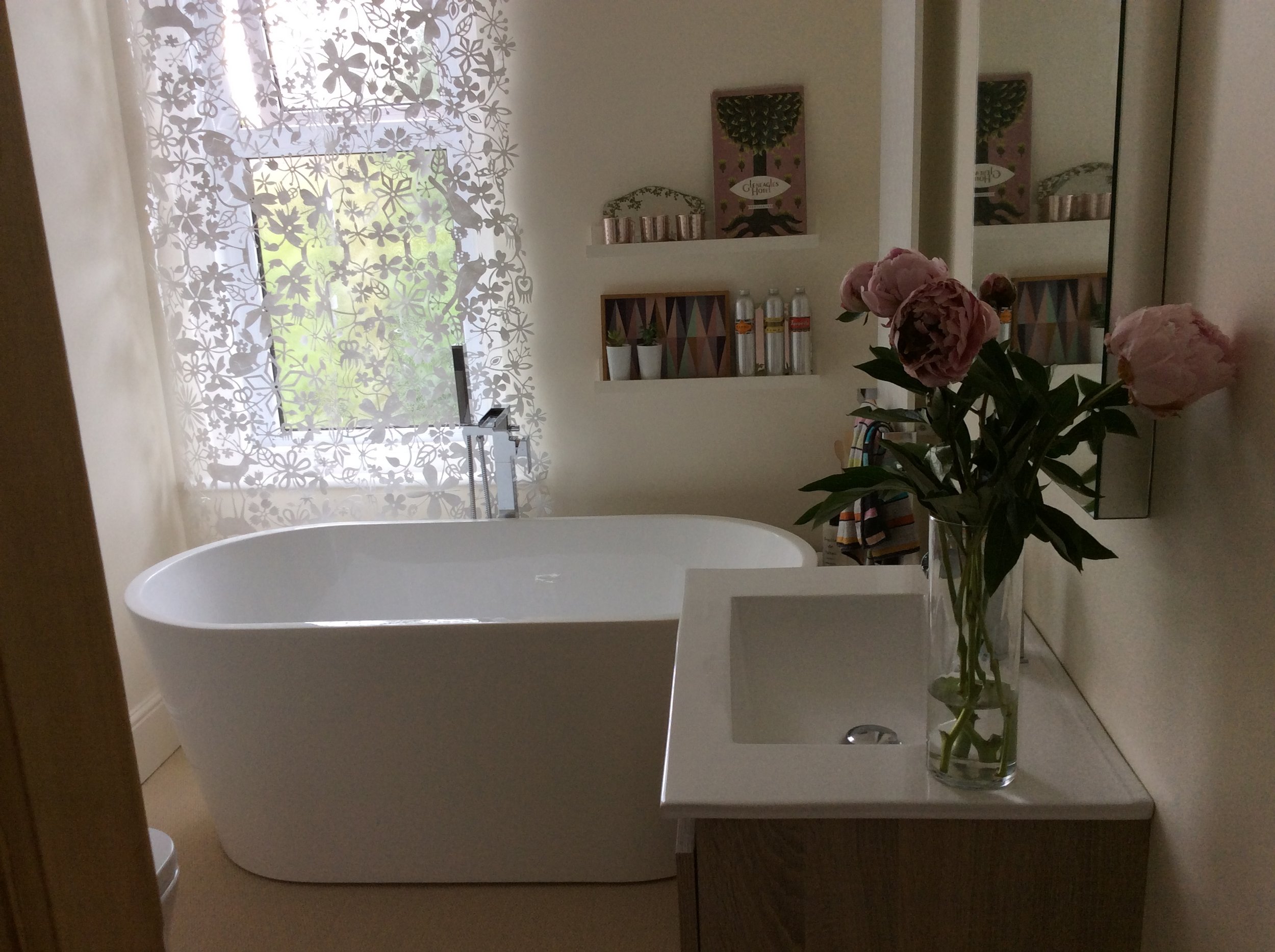 Tord Boontje lace bathroom window panels creating decorative light patterns above a freestanding bath.