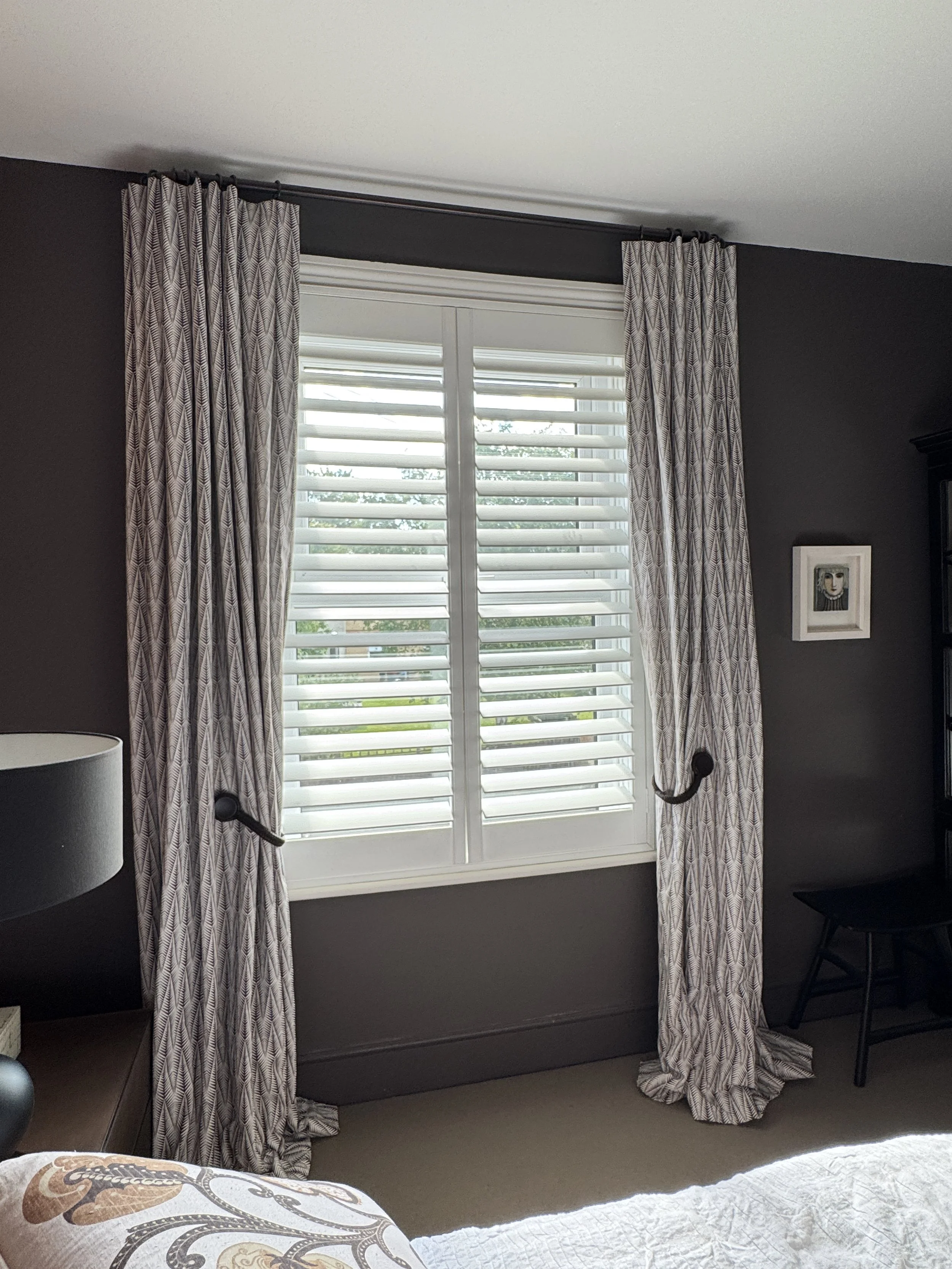 Main bedroom with bespoke Neisha Crosland Small Zebra curtains, white plantation shutters and colour-matched walls in deep smoky tones.