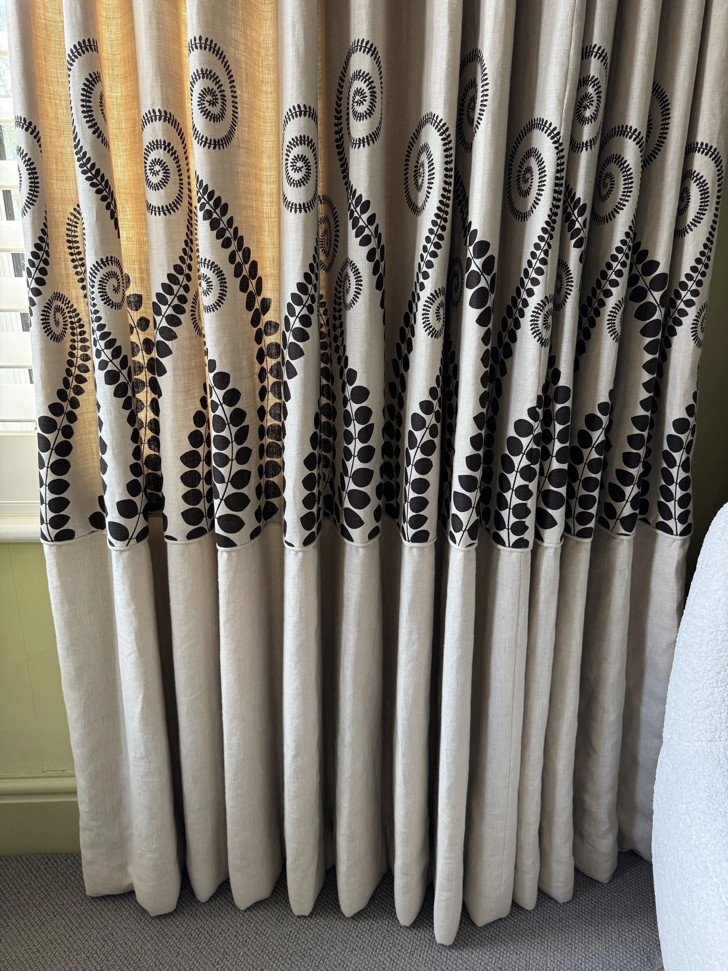 Close-up of bespoke curtains showing carefully positioned fabric motif, decorative piping and contrast linen border.