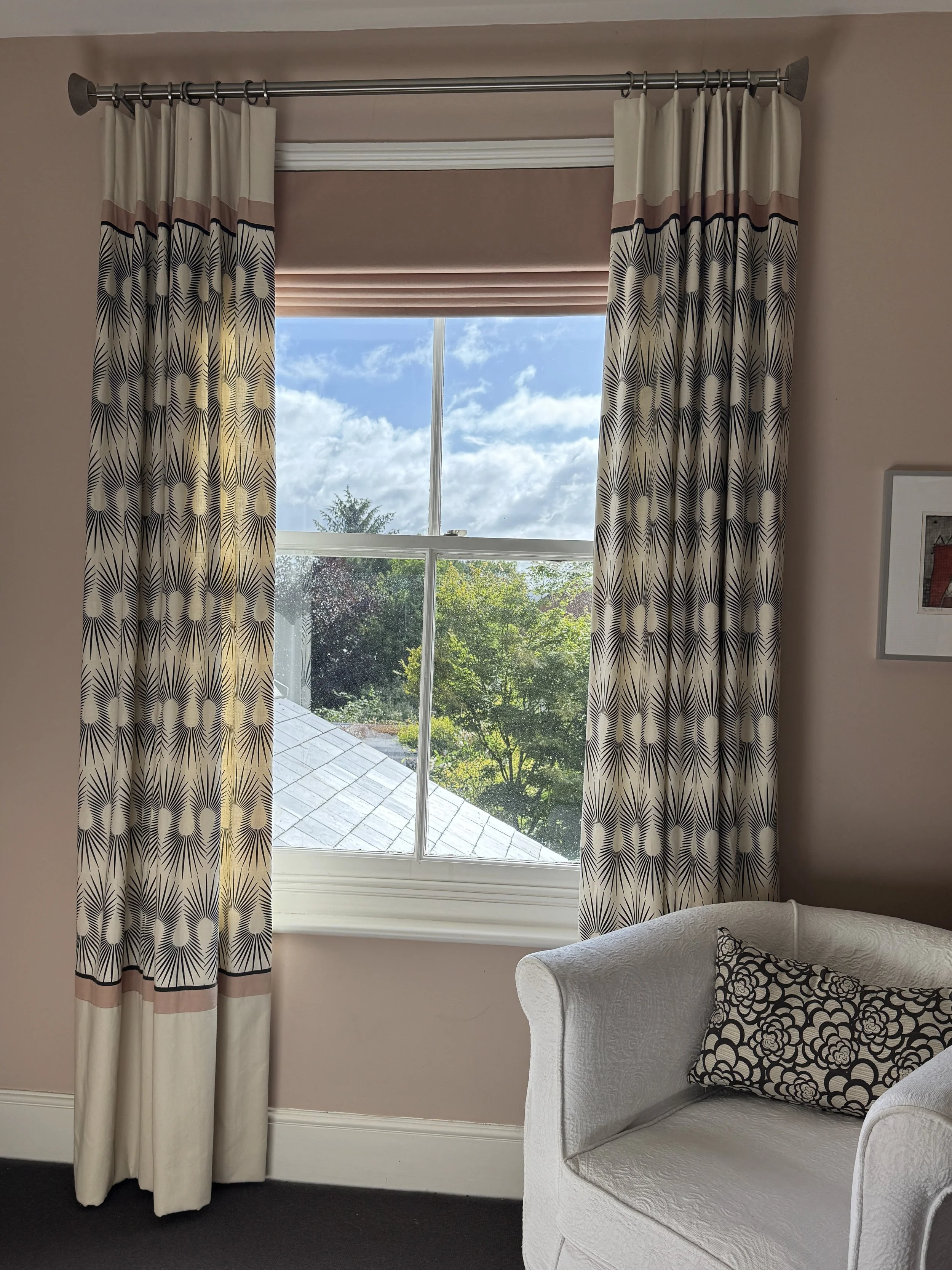 Guest bedroom window with bespoke Neisha Crosland curtains, contrast plaster pink bands and coordinating Roman blind.