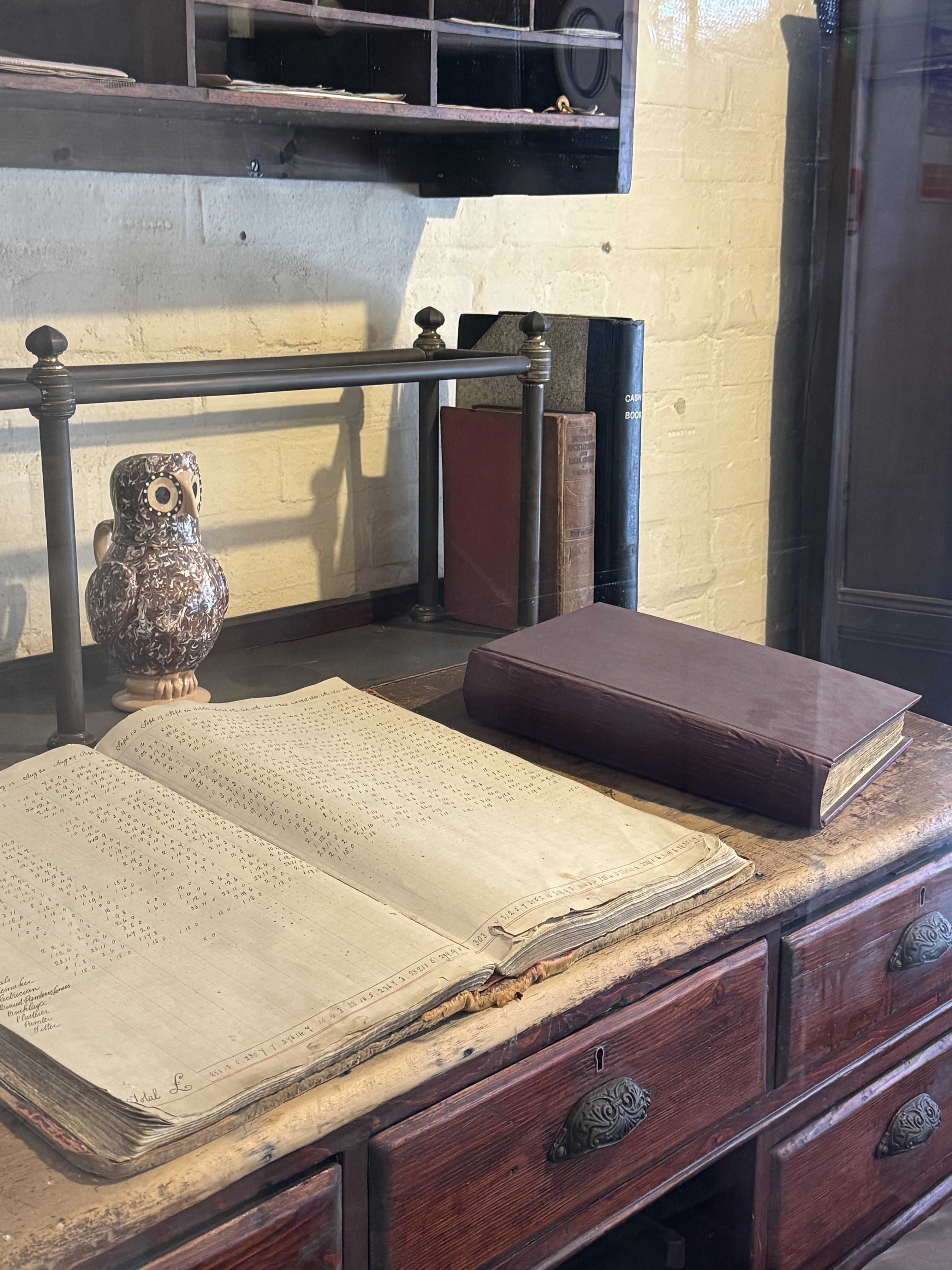 Pottery owl on an office desk beside an open ledger, Gladstone Pottery Museum