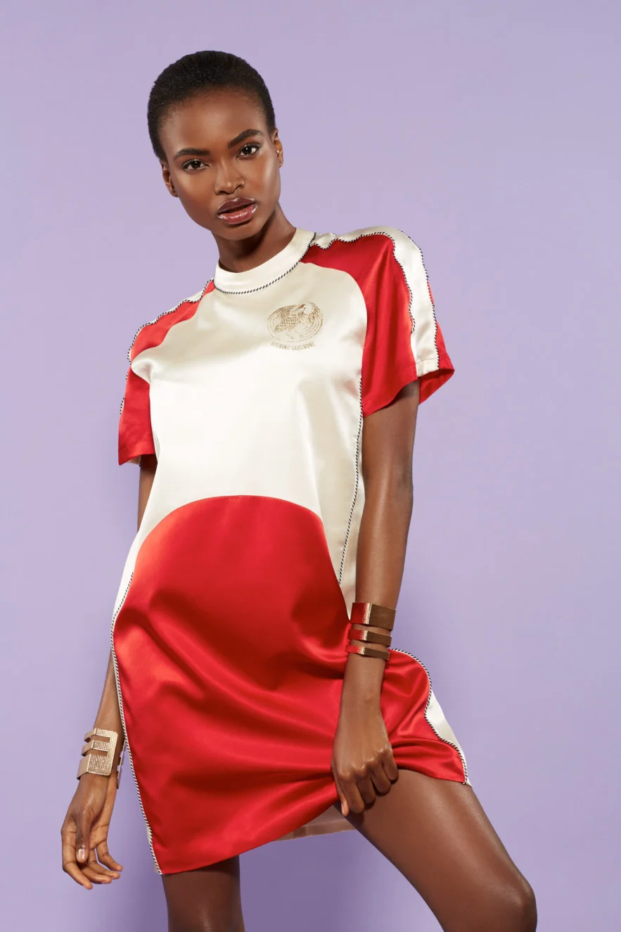 Female fashion model wearing athleisure apparel. Red and white satin color blocked dress by Opening Ceremony, and matching chunky gold cuffs. Photographed in New York City on lavender backdrop. Team Credits: Wardrobe styling by Darryl Anderson, hair and makeup by Amanda Holley