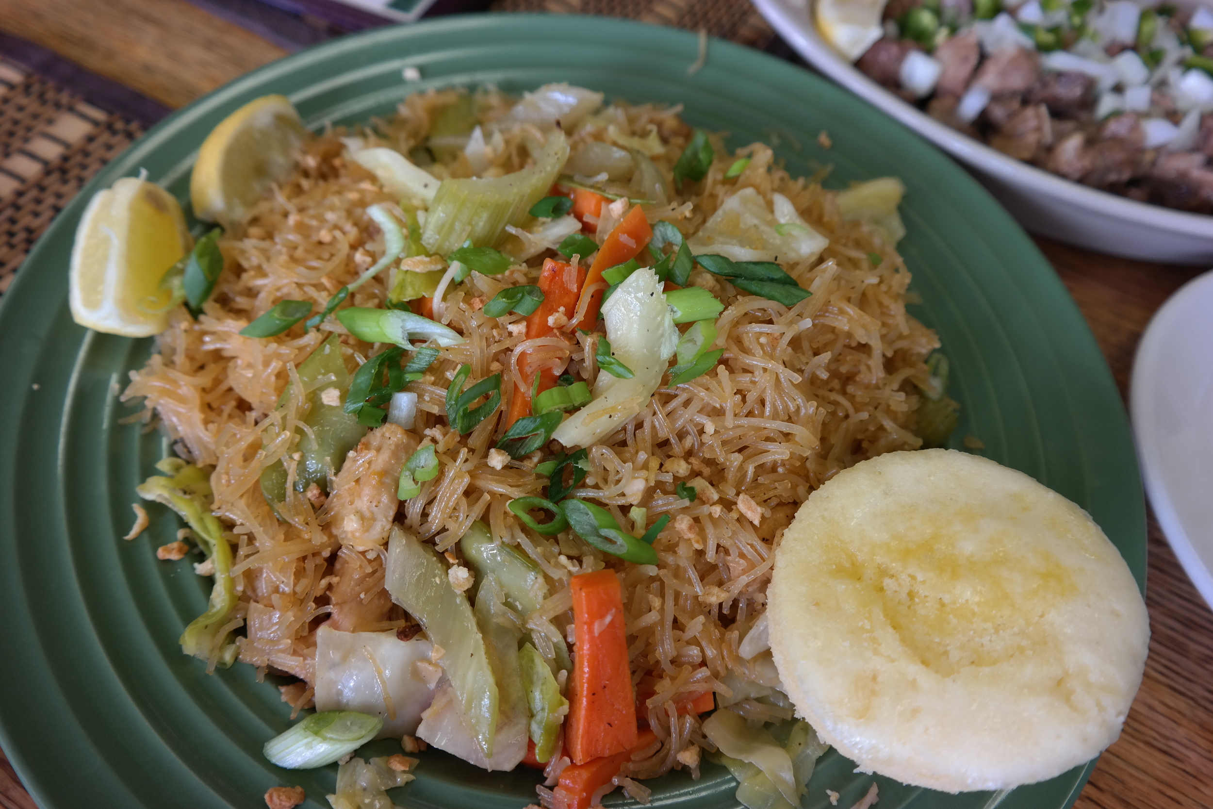 Pancit, rice noodles with vegetables and chicken and served with puto (steamed rice cake)