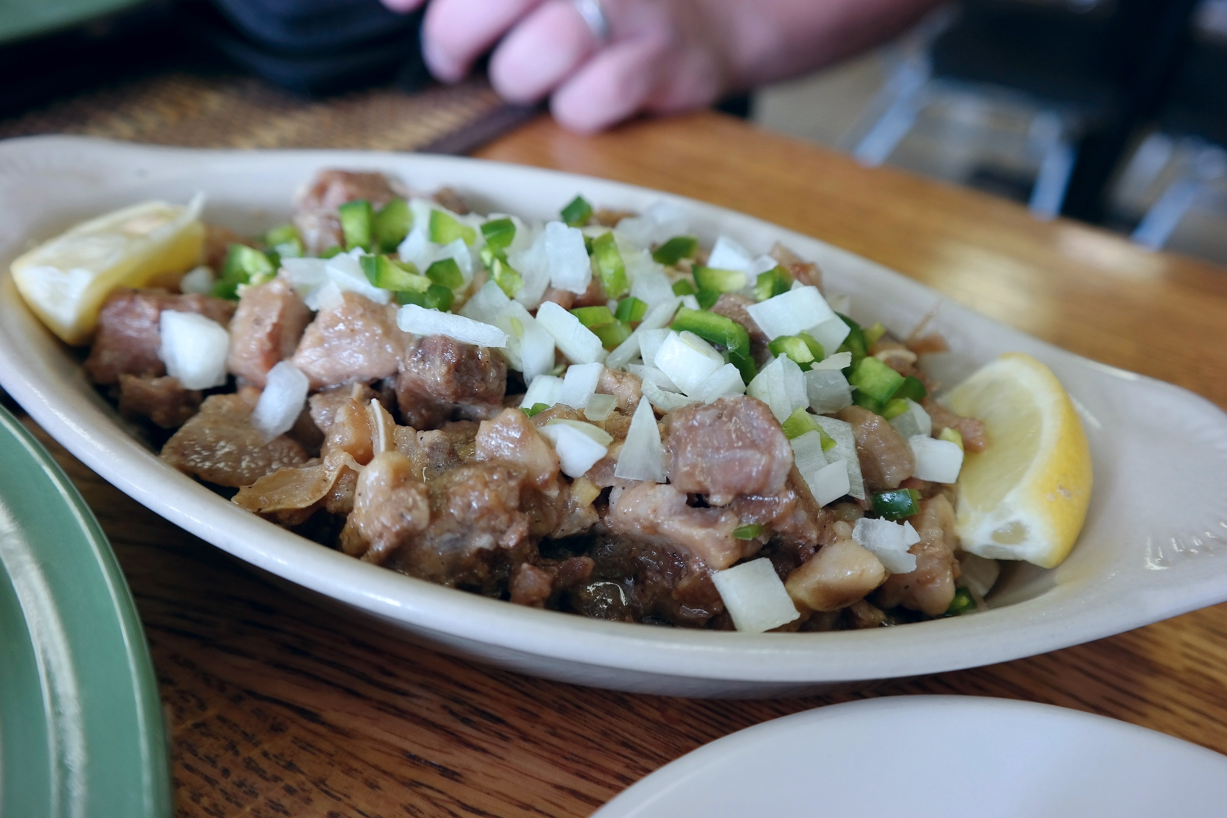 Sisig - chopped pork including pig ears and jowl sauteed with garlic and onions, garnished with jalapenos