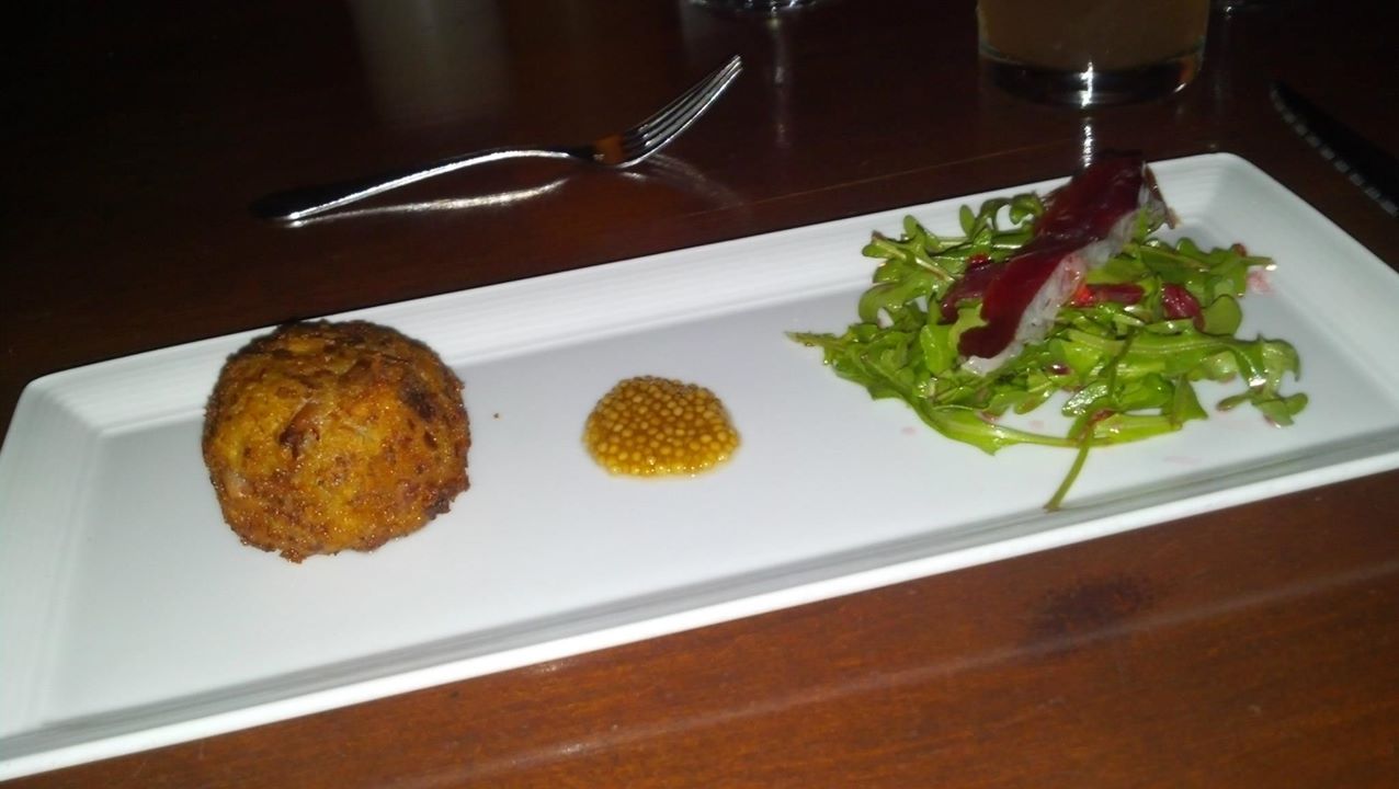 Duck confit croquette with pretzel-bread crust, confit mustard seeds, arugula, duck prosciutto, and blood orange vinaigrette