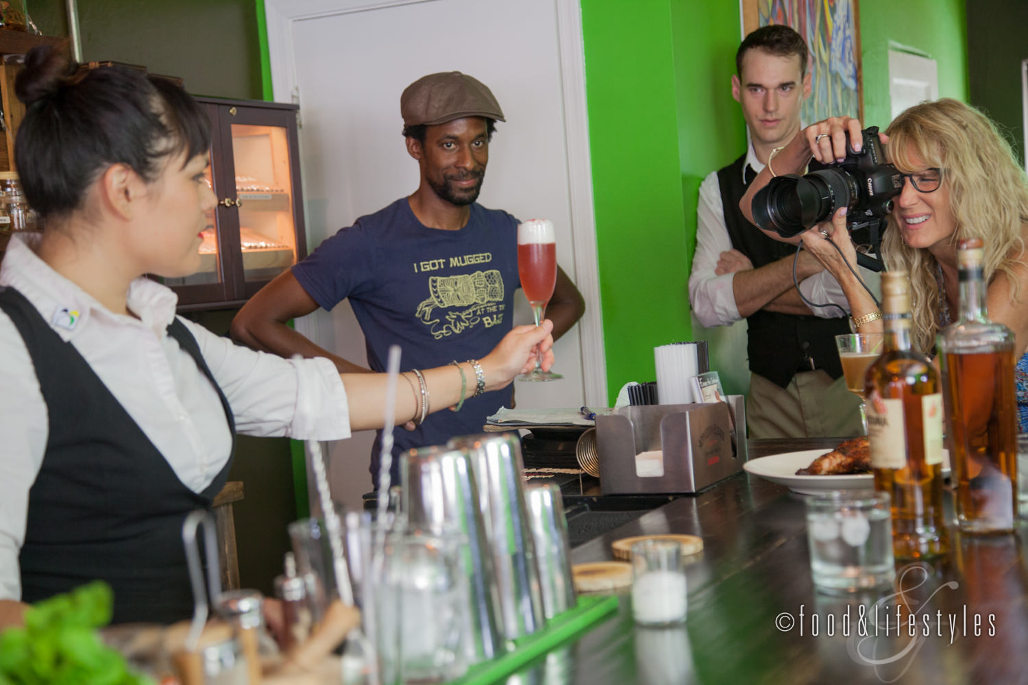 Danielle Goldtooth holds a Coconut Bramble as Debby Wolvos takes the shot and bartender Bryan Burton and owner Dwayne Allen look on.