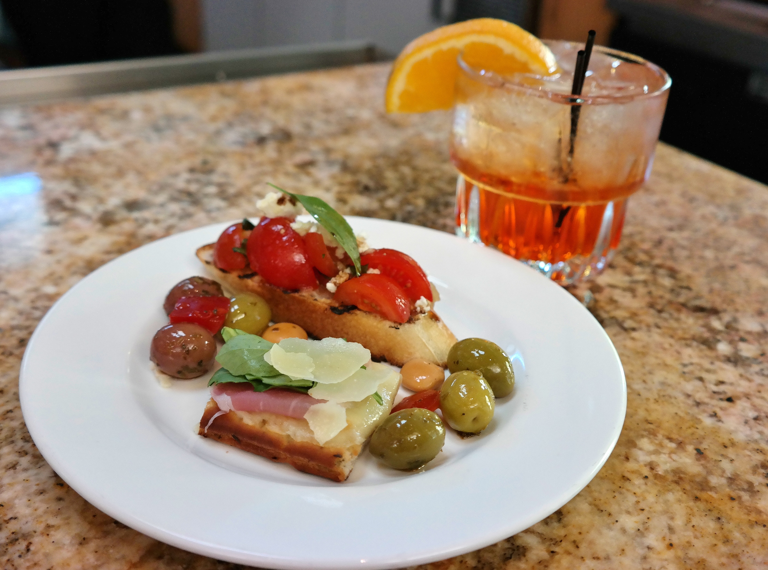 New-Groni (Bulldog Gin, vermouth bianco, infused Aperol, and orange bitters) with a complimentary snack plate. 