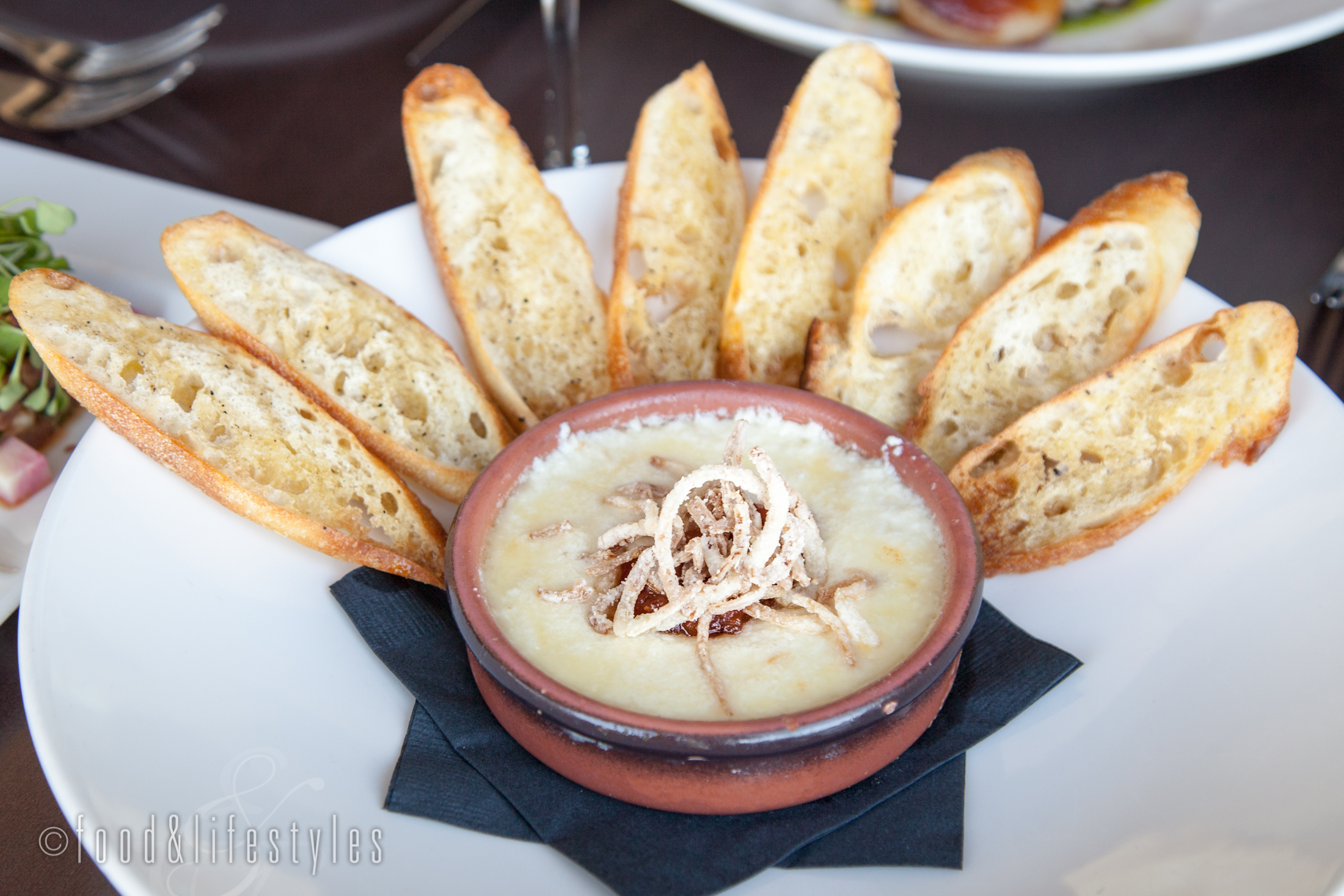 Baked goat cheese fondue with fried shallots and crostini