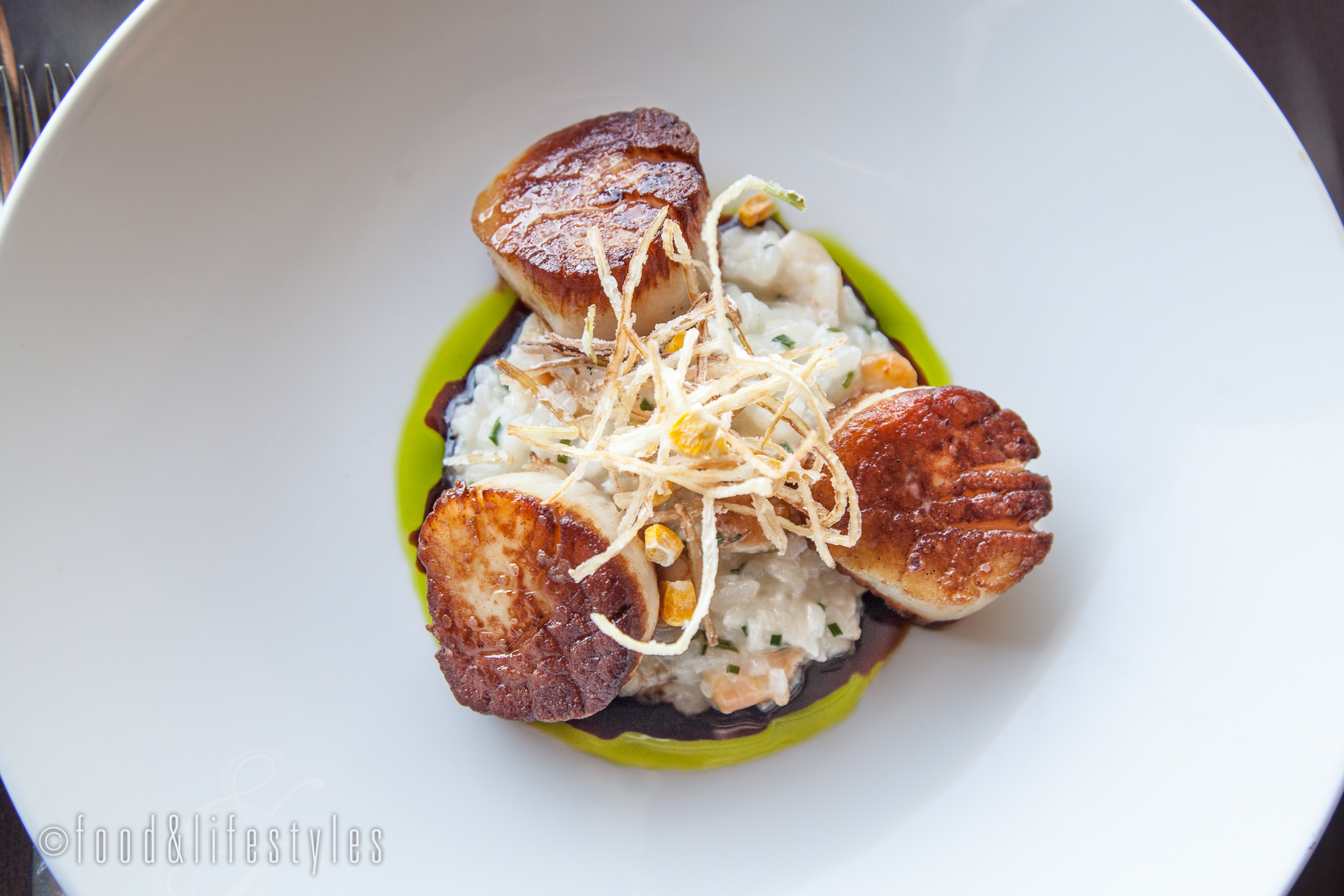 Seared scallops with smoked rock shrimp risotto, saba, chive oil, and crispy leeks 