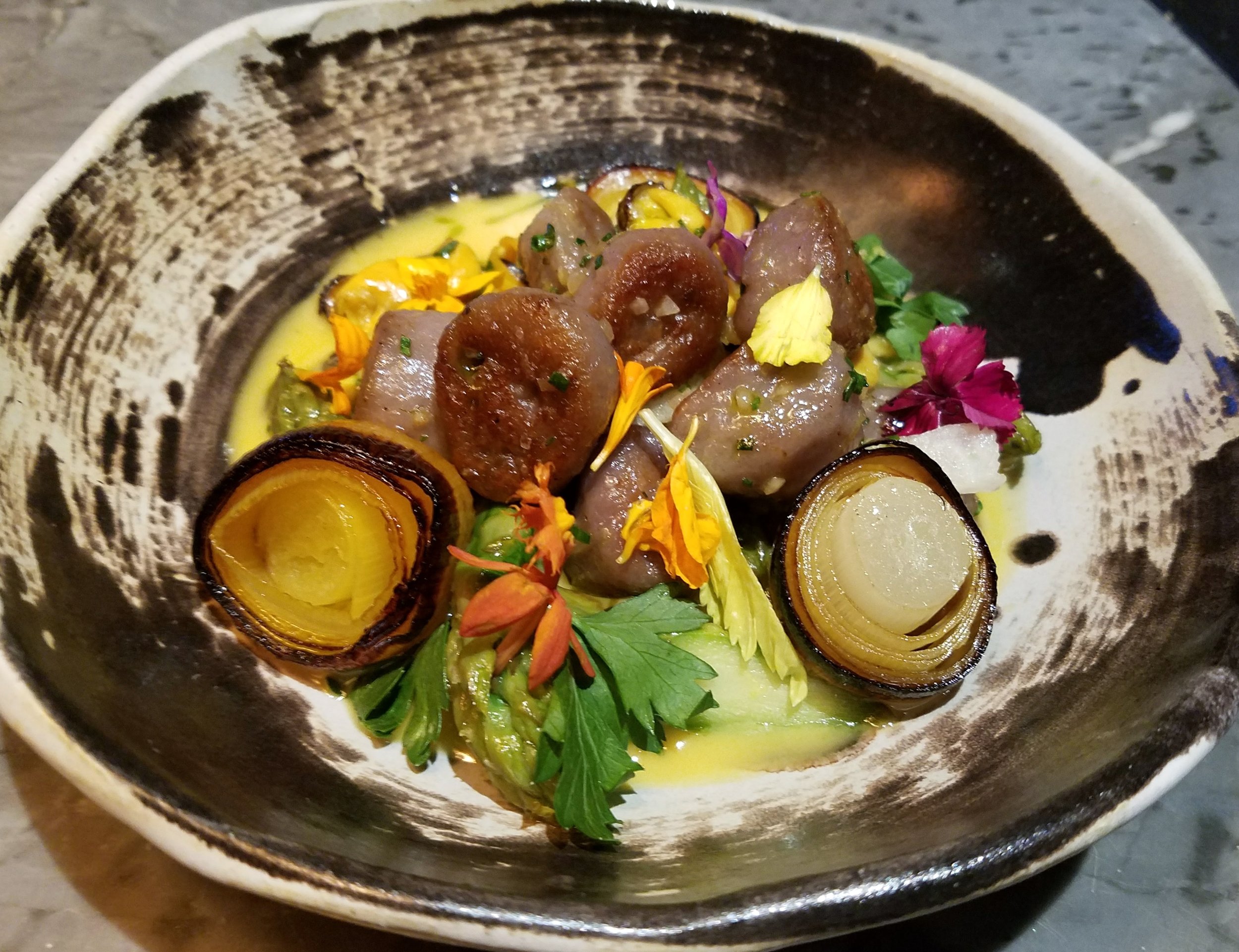 Purple potato gnocchi with saffron-poached mussels, charred leeks, asparagus, and a saffron beurre blanc
