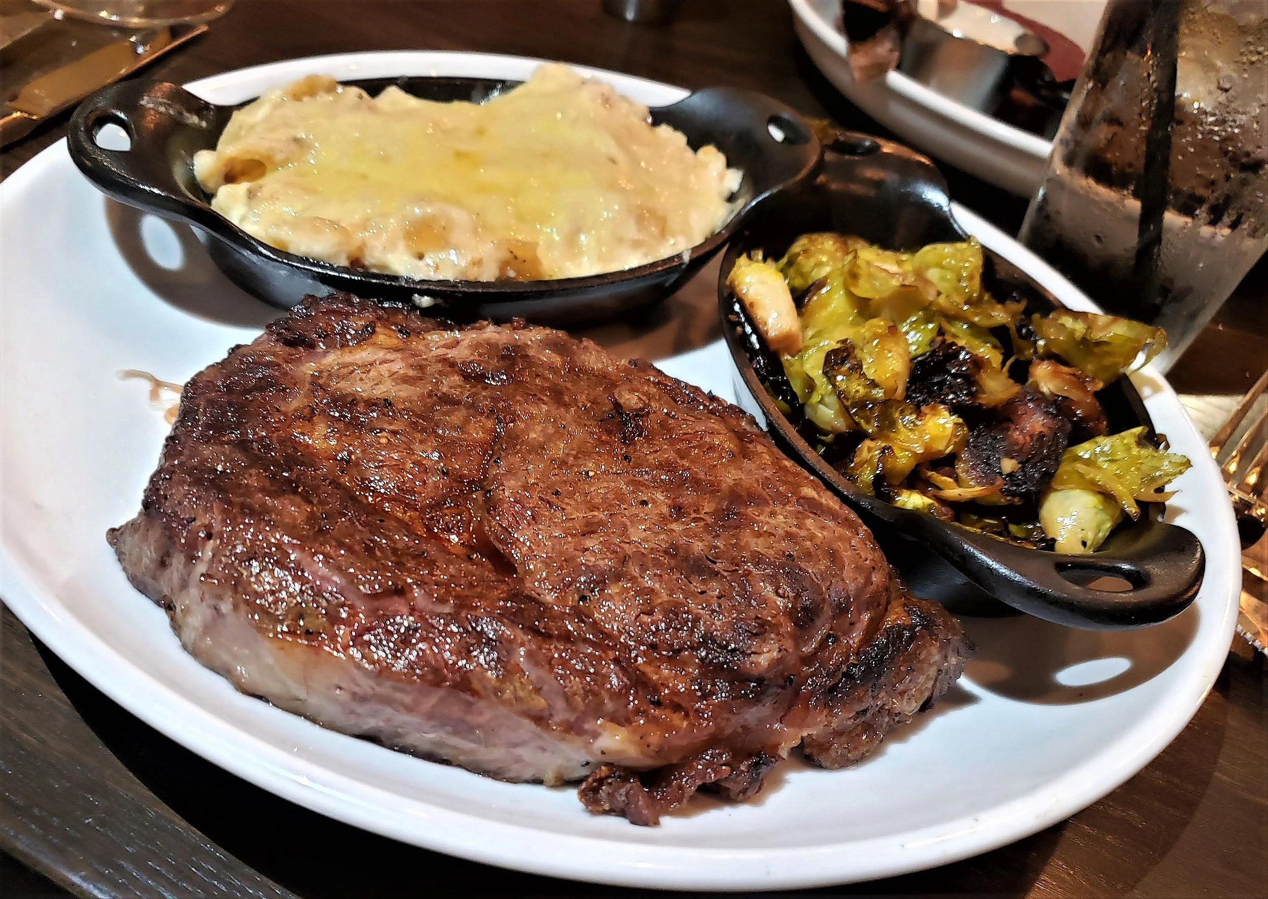 USDA Prime 18-oz ribeye with sides of scalloped potatoes and Brussels sprouts (Christina Barrueta)