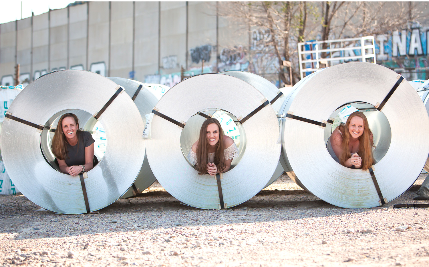 High School Senior and her mom and sister in rolls of sheet metal in a materials yard in Denver. Photographer Jennifer Koskinen, Merritt Design Photo