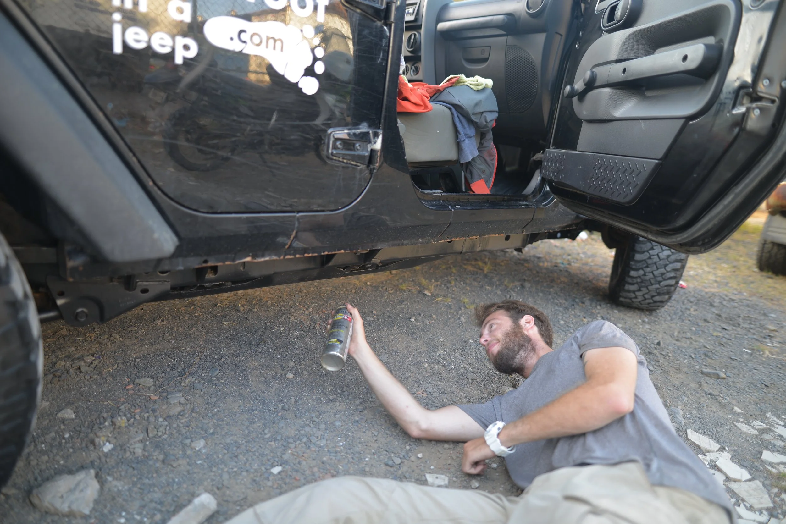 Spraying the bottom of the Jeep with a rust-proof black paint.