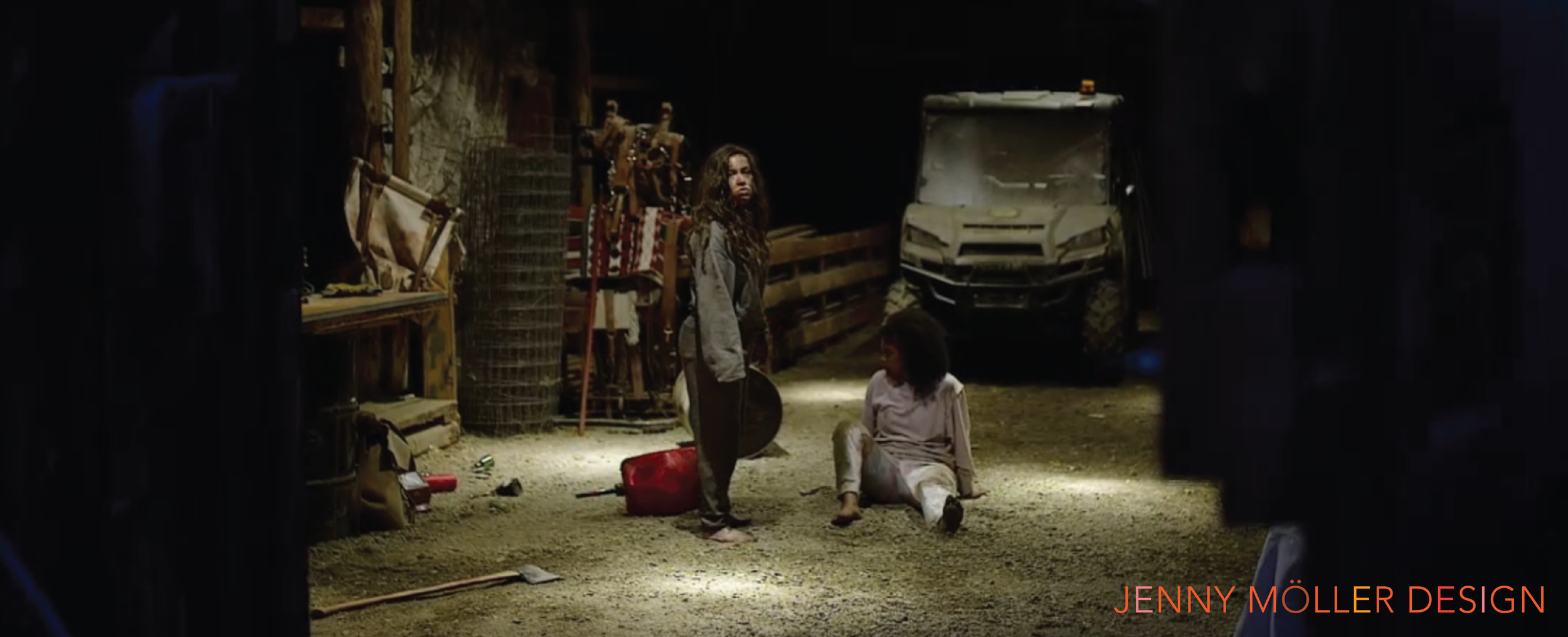Two young girls in a dark barn or warehouse with various objects and equipment around, one standing with a guitar and the other sitting on the ground. There is a van in the background and the scene is dimly lit.