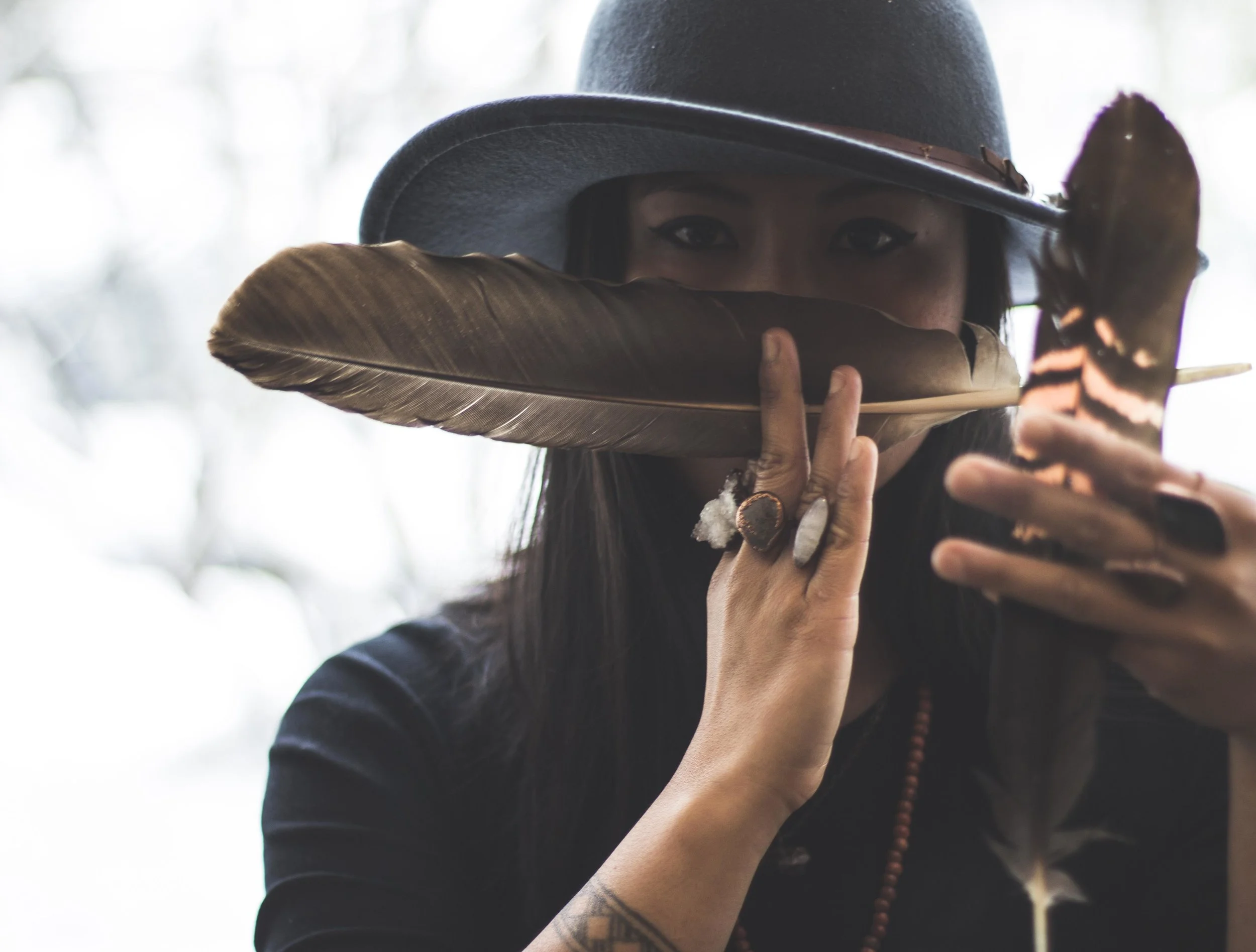 Woman with feathers in hand and crystal jewellery on hands