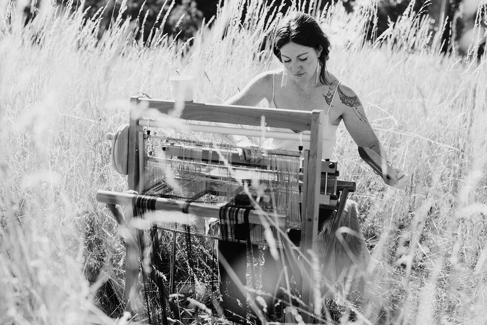 Women weaving in a field with SAORI loom