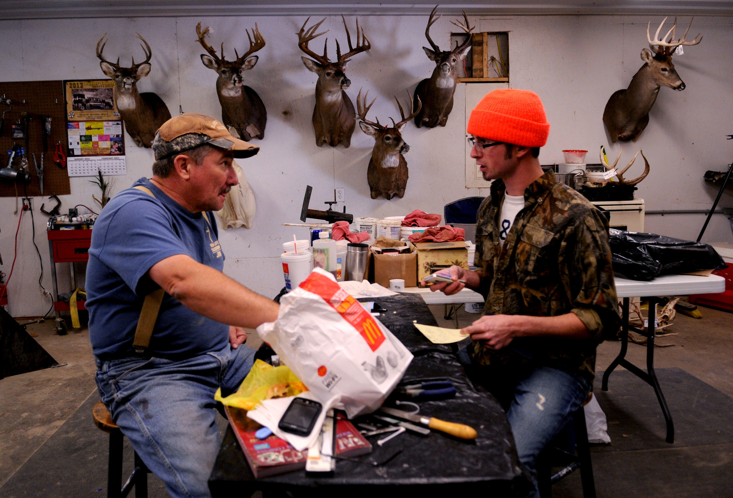 Jim McIntosh (left), of Morgantown, Kentucky, eats lunch and talks with customer Justus Eaton (right), on Friday, November sixteenth, about the specifics of what kind of deer mount he would like. Eaton traveled from North Carolina specifically to hu