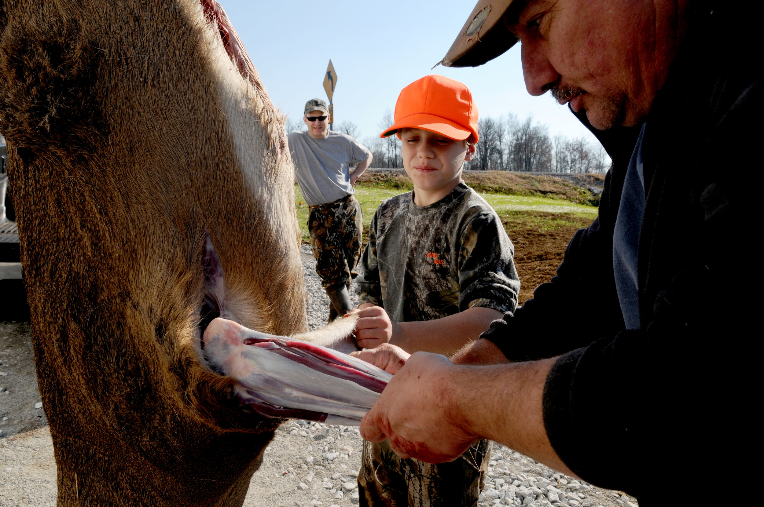  Bob McPherson (left) watches as his son Andrew, 10, (center) helps Jim McIntosh (right) skin a deer that Andrew shot earlier that day outside 'Jims New Life Taxidermy' on Friday, November sixteenth. This deer, which was Andrews first ever, will be p