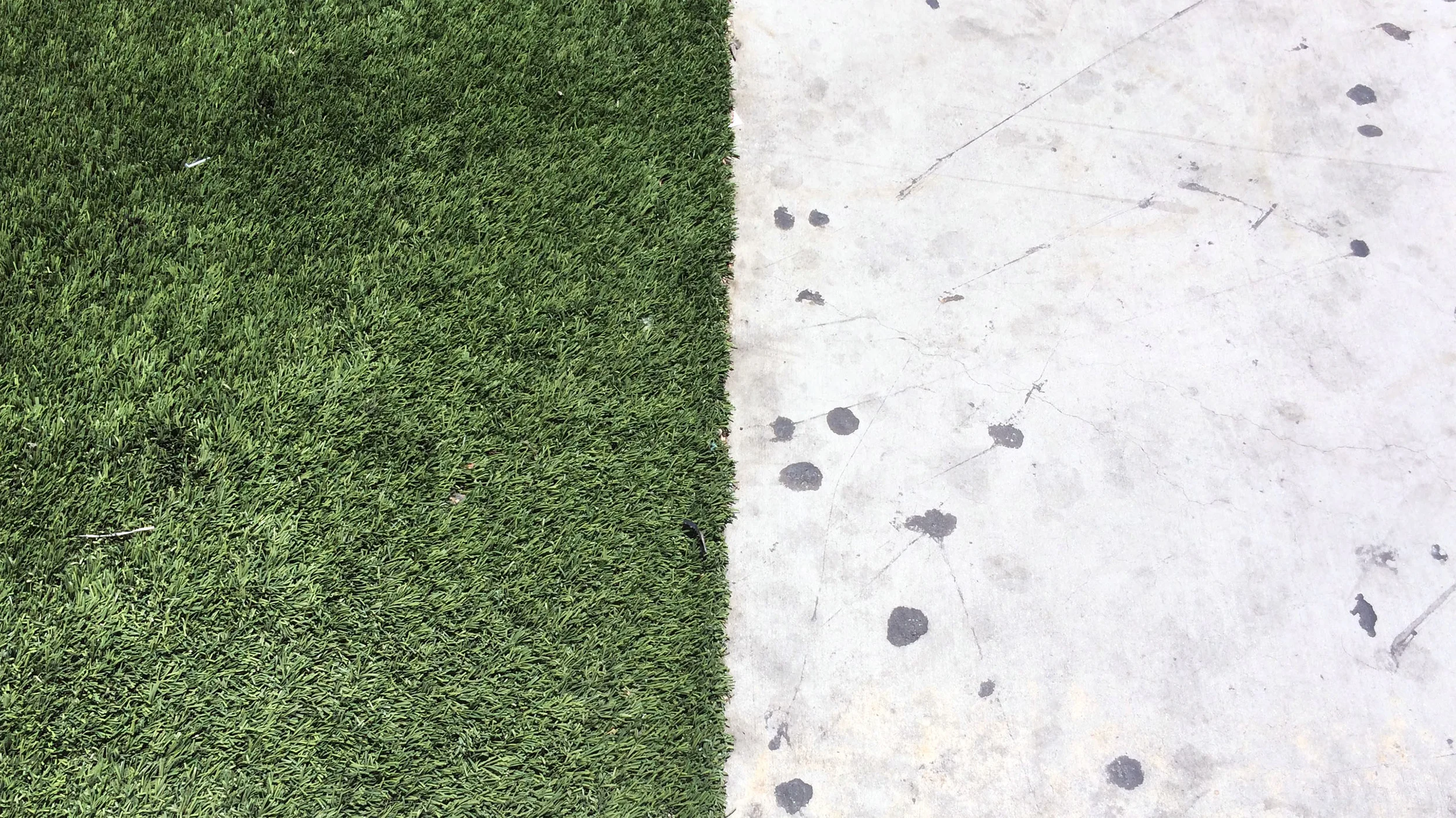 A hard divide between concrete and synthetic turf on a sidewalk on Los Angeles Street in the Skid Row neighborhood of Downtown Los Angeles. (Photograph by Ian Besler)