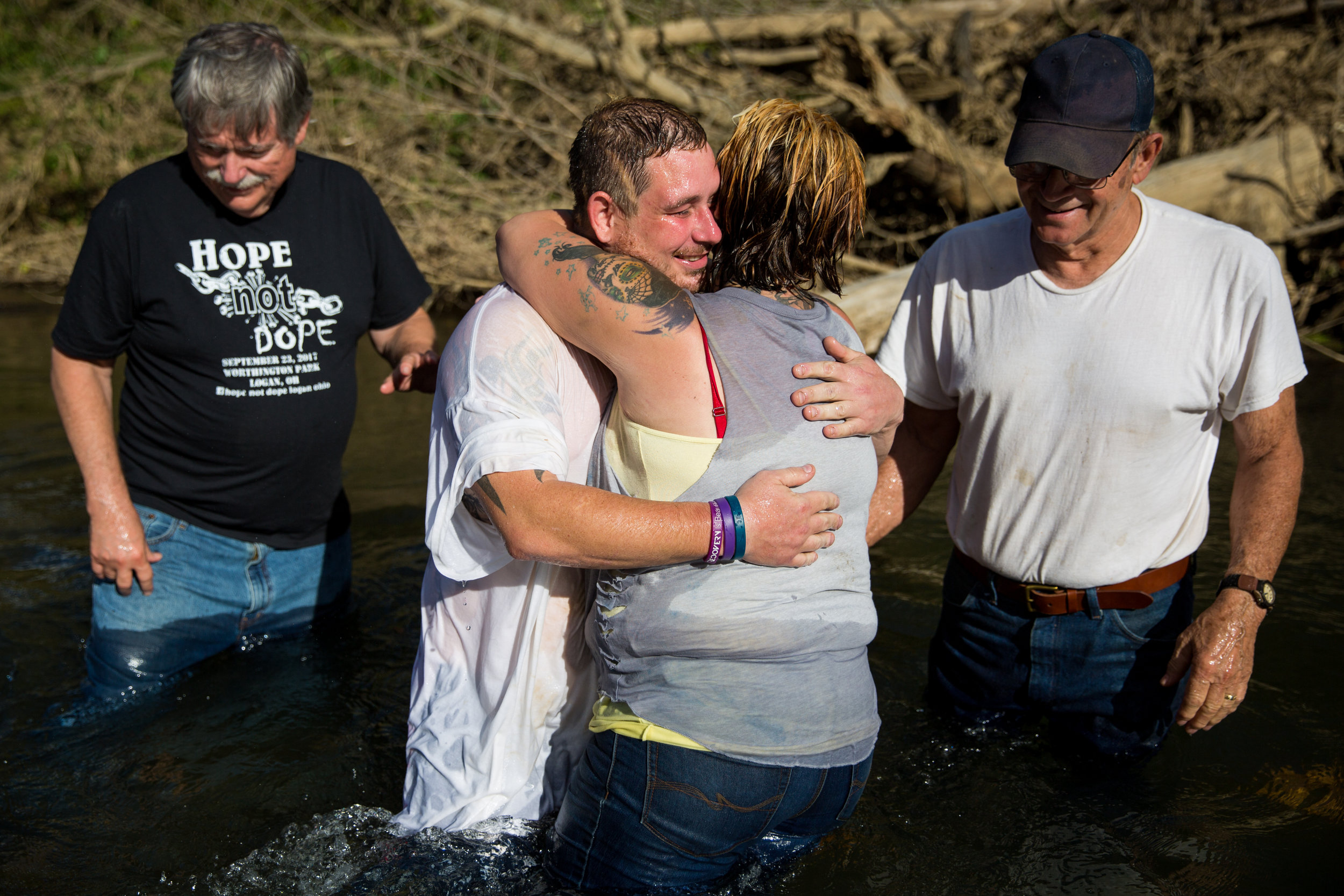  Whitney hugs Jeremy after his baptism by Pastor Bruce Livingston, left, and Whitney's adoptive father, Larry Swart, right. Jeremy has known Pastor Livingston since he was a child and sees him as a sort of father figure. 