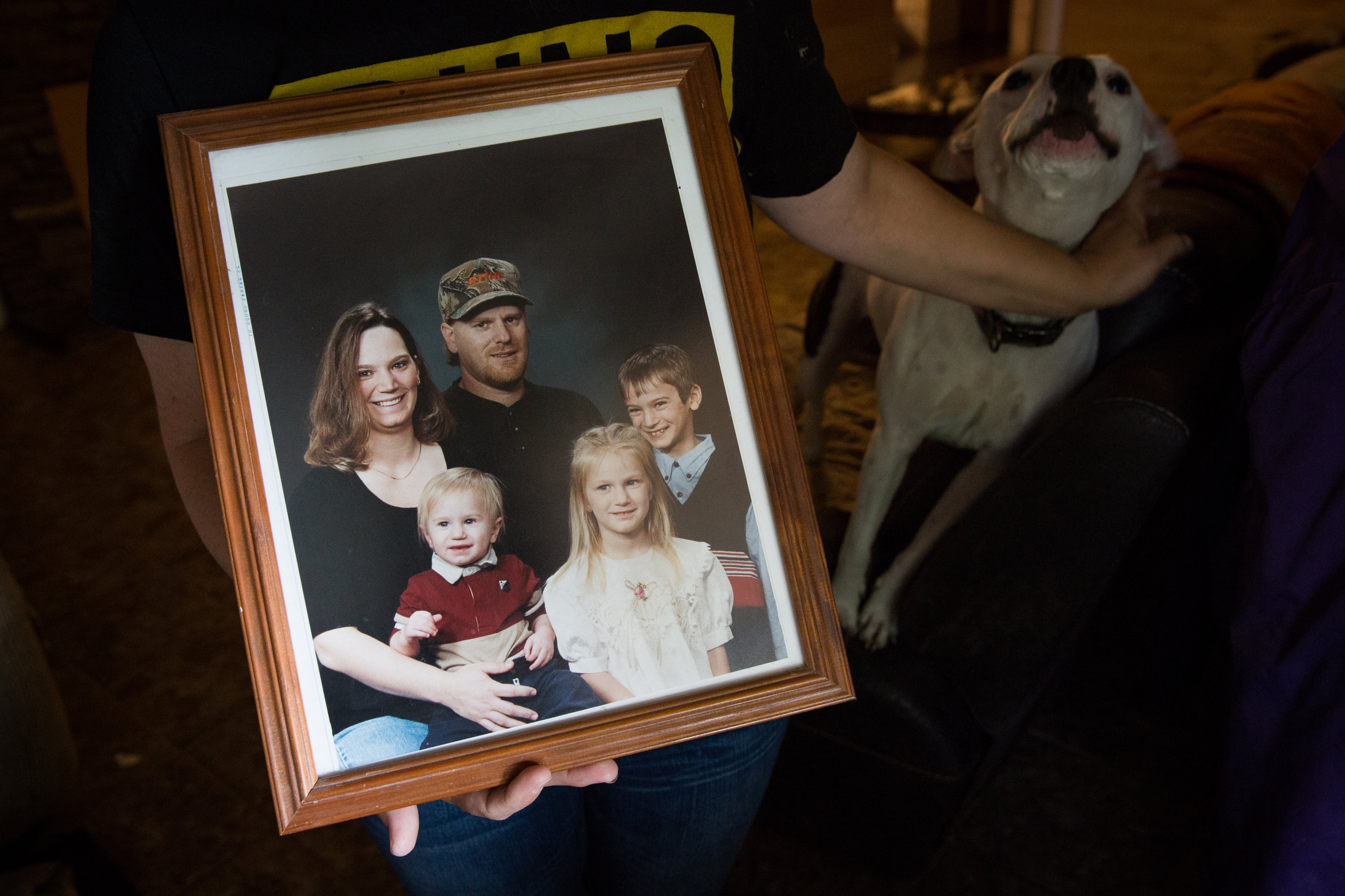  Missy holds up the last professional portrait her family had taken more than 10 years ago while holding back Reese Cup, a pit bull that her son brought home. Missy didn't want the dog to be uprooted every time her son left, so she opted to keep her.