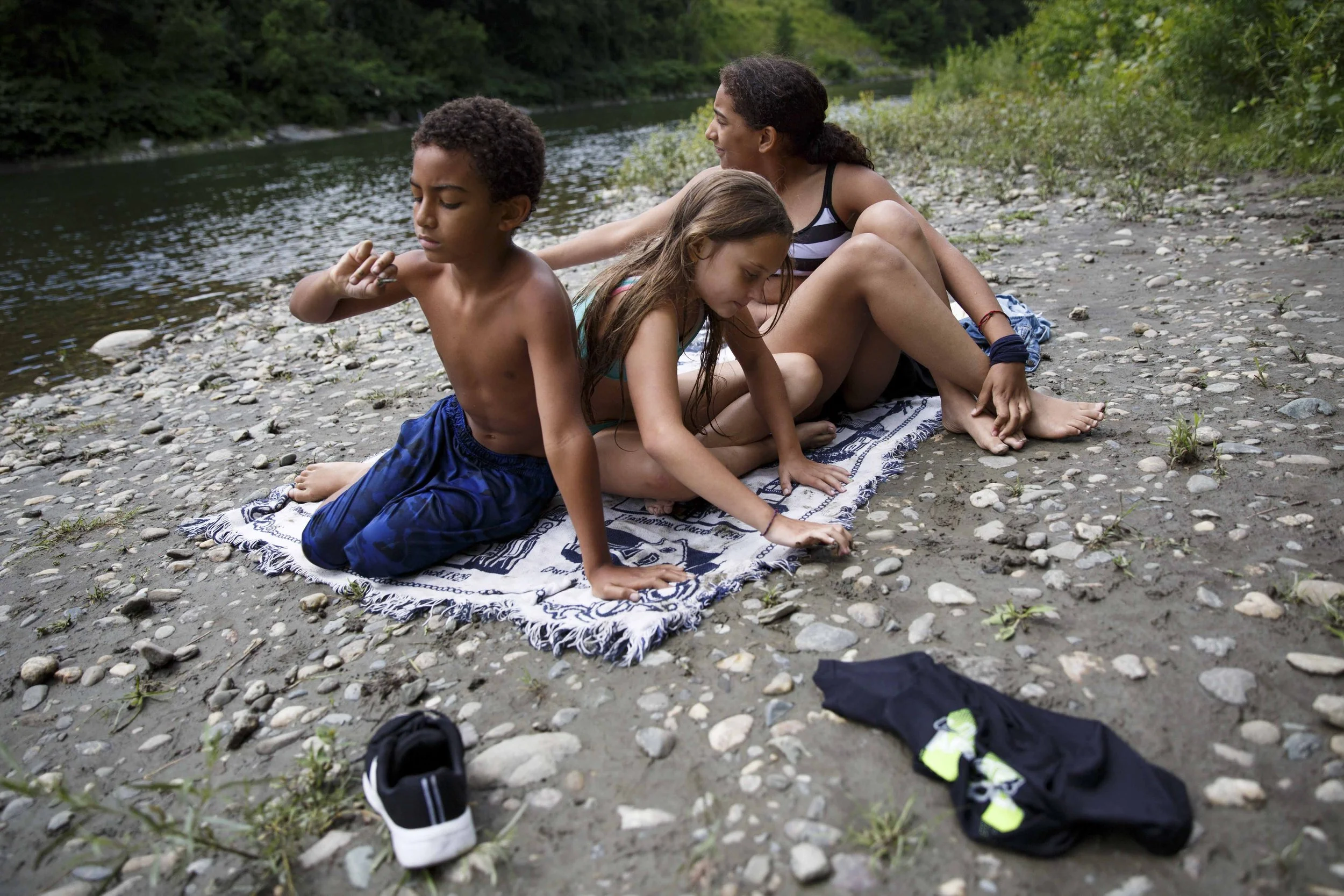  From left, siblings Kendrick Gardner, 8, of White River Junction, Vt., Cecelia Theriault, 10, of White River Junction, Vt., and McKenzie Gardner, 12, of Canaan, N.H., look for good rocks to throw into the White River at Watson Park in Hartford Villa