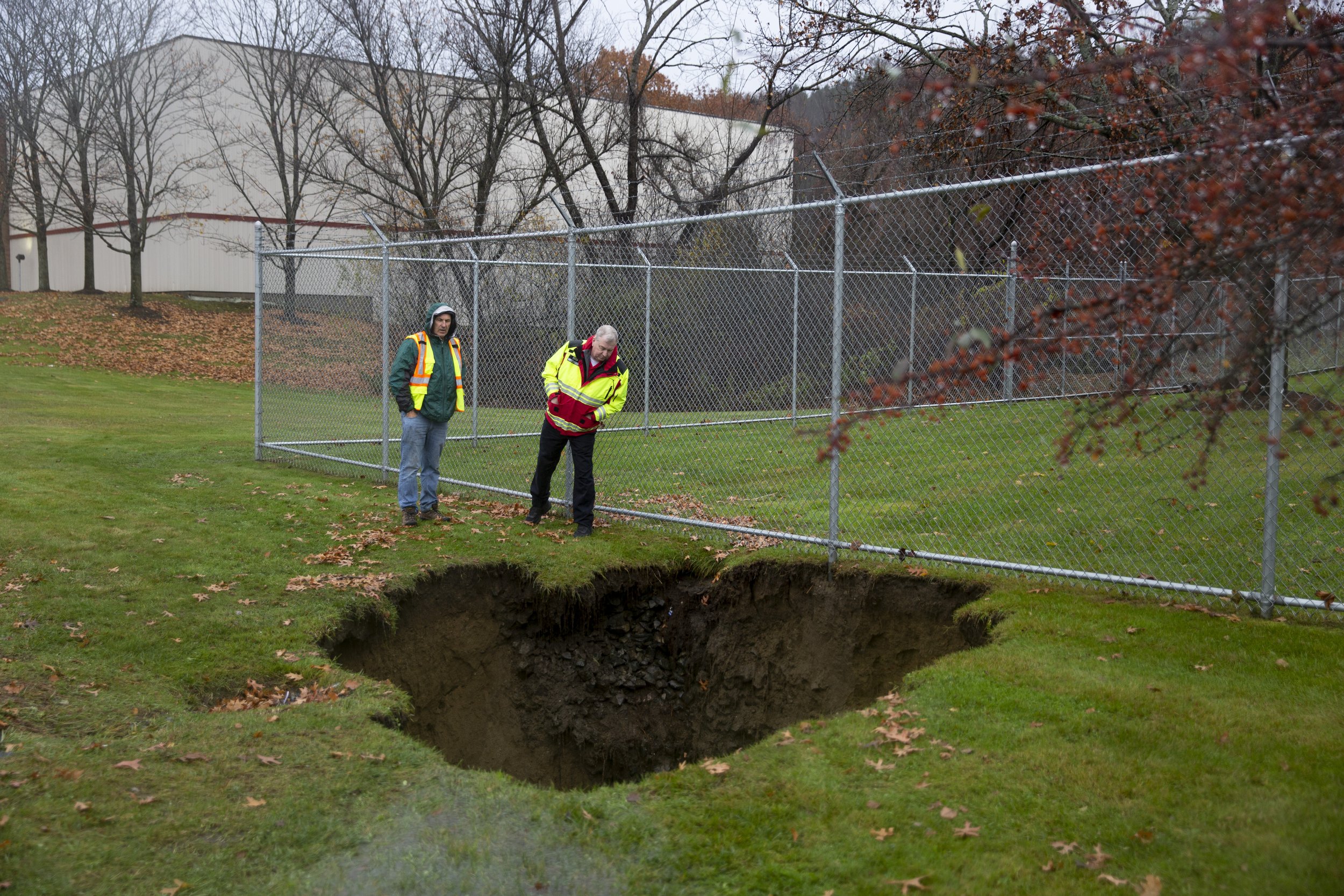  Jim Donison, left, who is the director of Lebanon's Public Works Department, and Lebanon Fire Chief Chris Christopoulos examine a sinkhole that opened up on Route 4 in front of Liberty Utilities in Lebanon, N.H., on Friday, Nov. 12, 2021. Donison sa