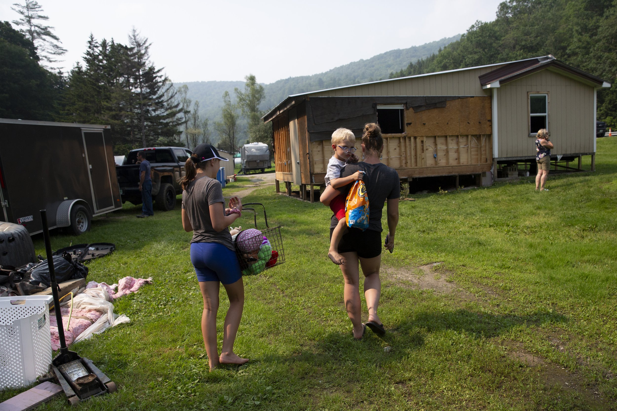  Casey Mispel carries her son Joe, 3, while she and her daughter Faith, 13, walk toward their flood-damaged home in Bridgewater, Vt., on Monday, July 17, 2023. The family was on vacation in Maine on July 10 when heavy rain caused their property to fl
