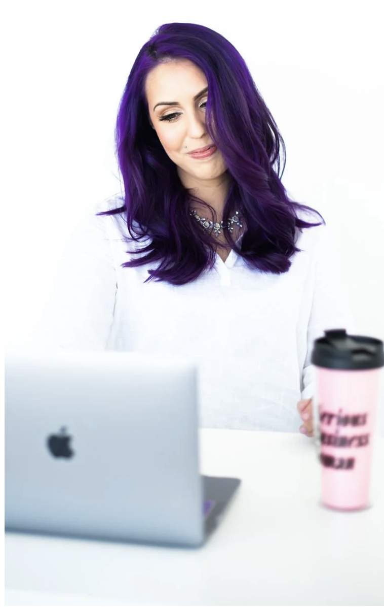 Hollie Berry of the Just Lago team seated at a laptop with vivid purple hair.