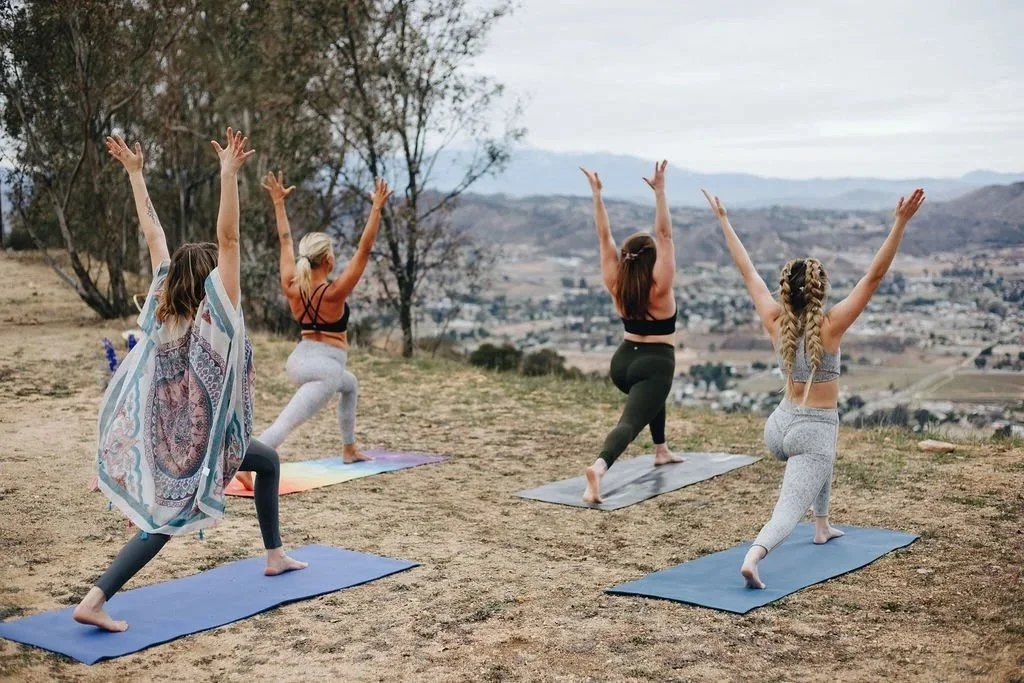 Three women practicing outdoor yoga as part of a bridal wellness experience.