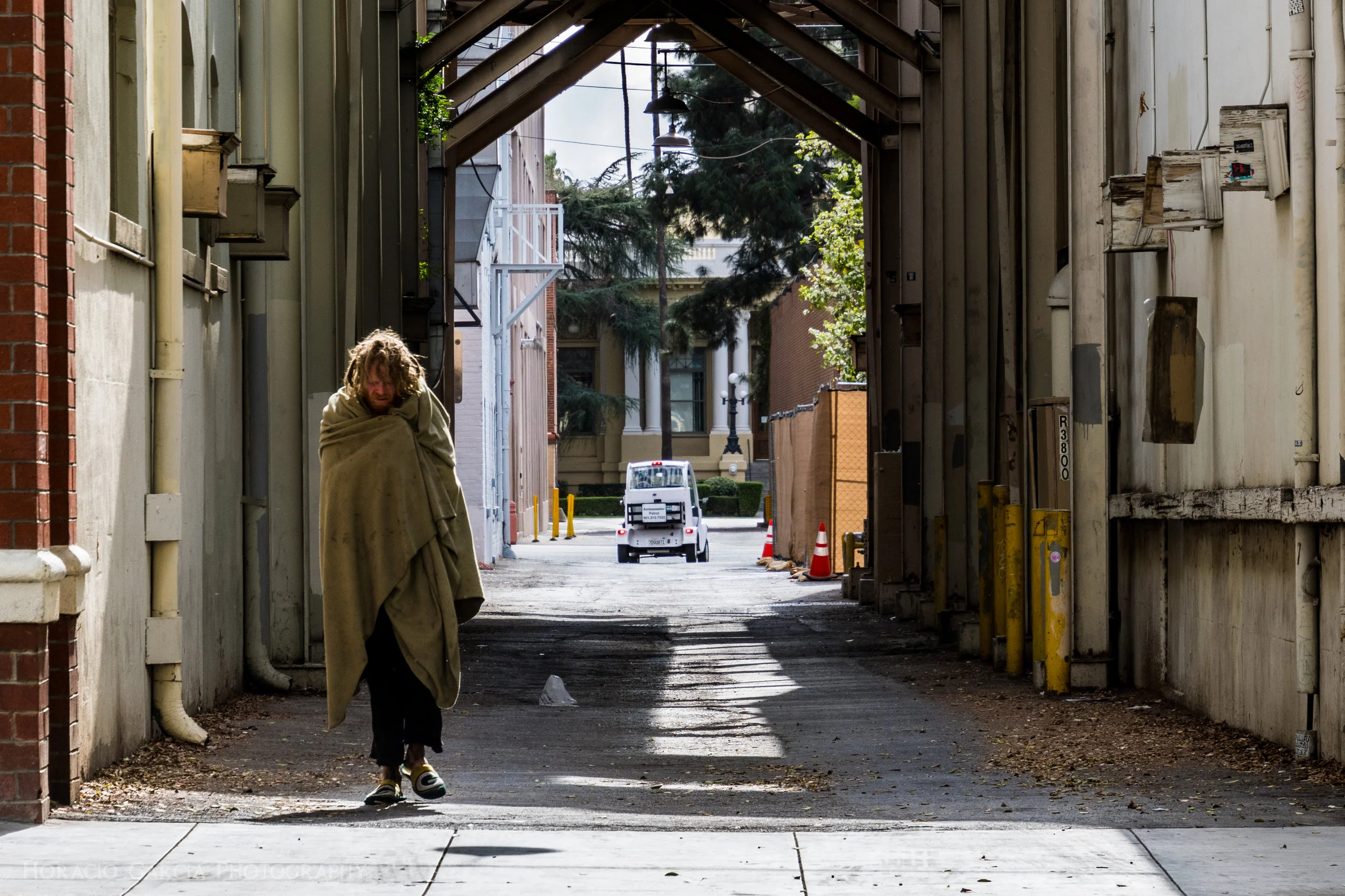 A homeless man walks through a back alley in Downtown Riverside