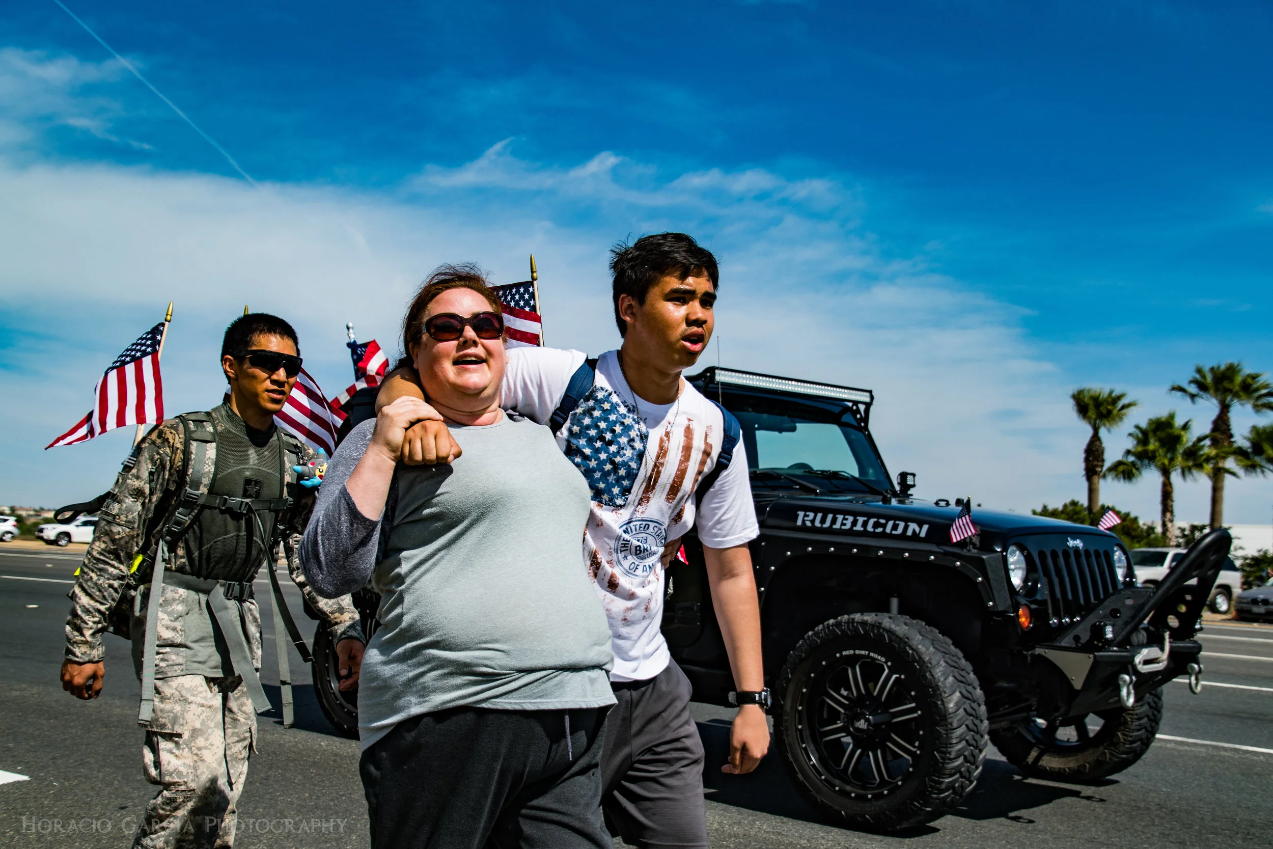 After nearly 40 Miles of walking, Jonah(right) is helped to complete the trek from Ganesha High School in Pomona to the Riverside National Cemetery. The roughly 14 hour walk, completed by Jonah and many others, was to bring awareness to Suicide Prevention among Veterans. Roughly 22 Veterans commit suicide per day. Each person walking carried a backpack that weighed 22lbs and flags with the photo of a Veteran attached to it whom had fallen to suicide.