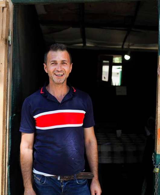 Fars stands outside the entrance to his falafel shop.