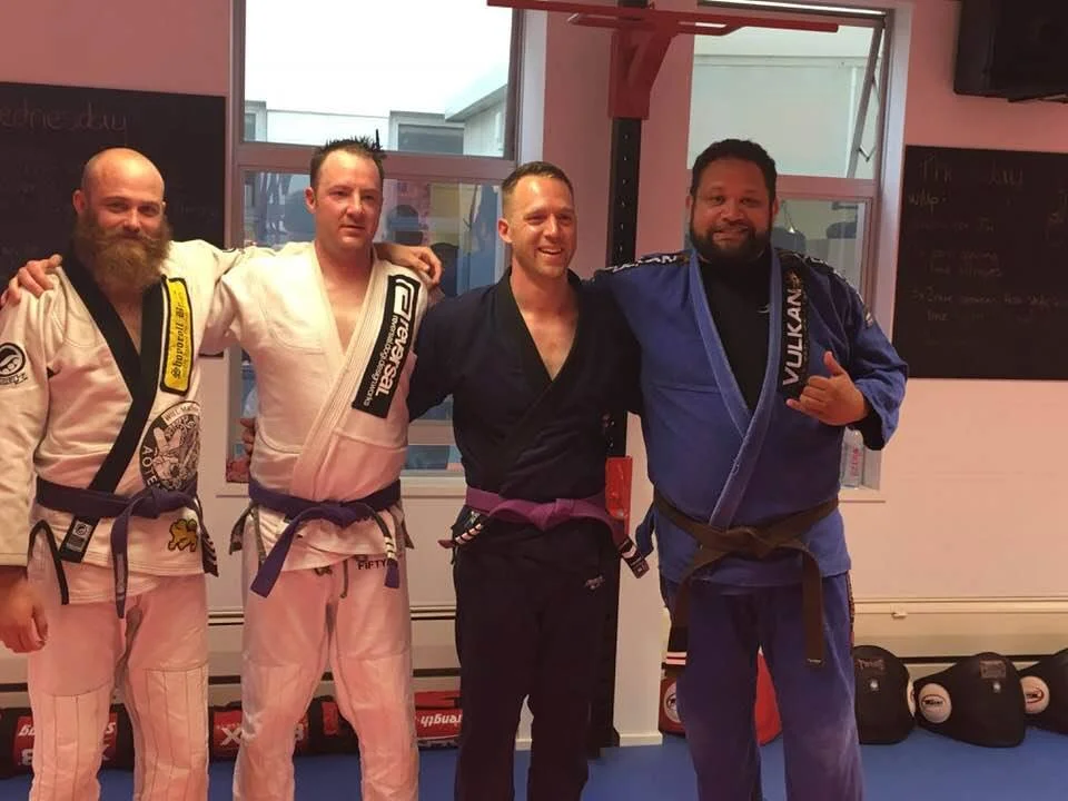 From left to right: Purple belts Andrew, Corrin, and Chris who achieved new tabs, and proud Coach Jay.