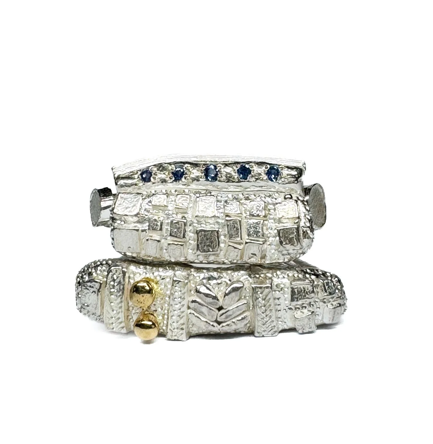 Series of One #143
Sterling silver set Ceylon sapphires and hand engraved.

Series of One #148
Sterling silver with 18ct yellow gold and hand engraved.

Both rings have irregular surfaces, catching the light with movement.

These rings are exclusive 