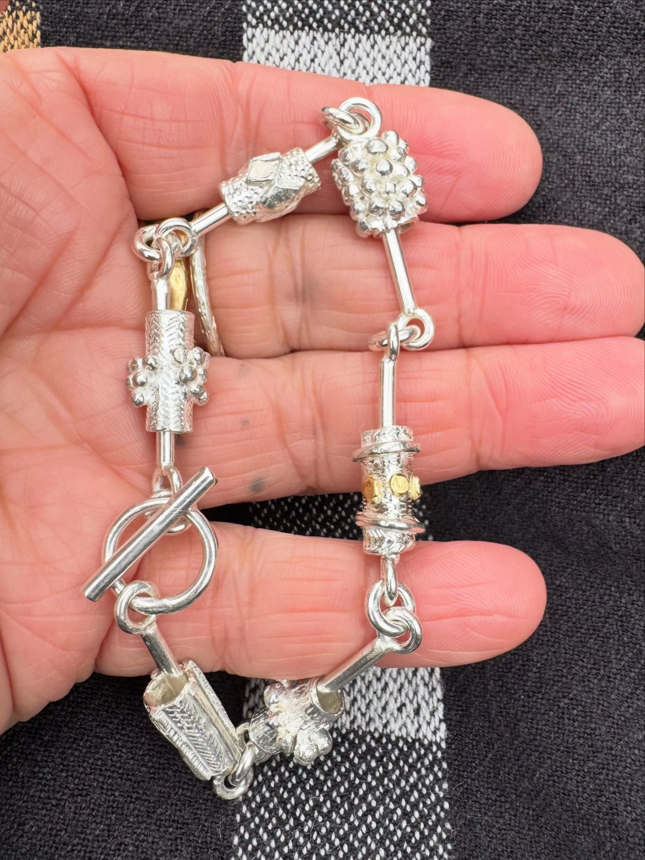 Sterling silver charm bracelet.
Series of One #172

The beads are suspended on bars to encourage play.

There is one of these bracelets and it is exclusive to the studio.

#handmade #charm #bracelet#katherinebowmanjewellery
