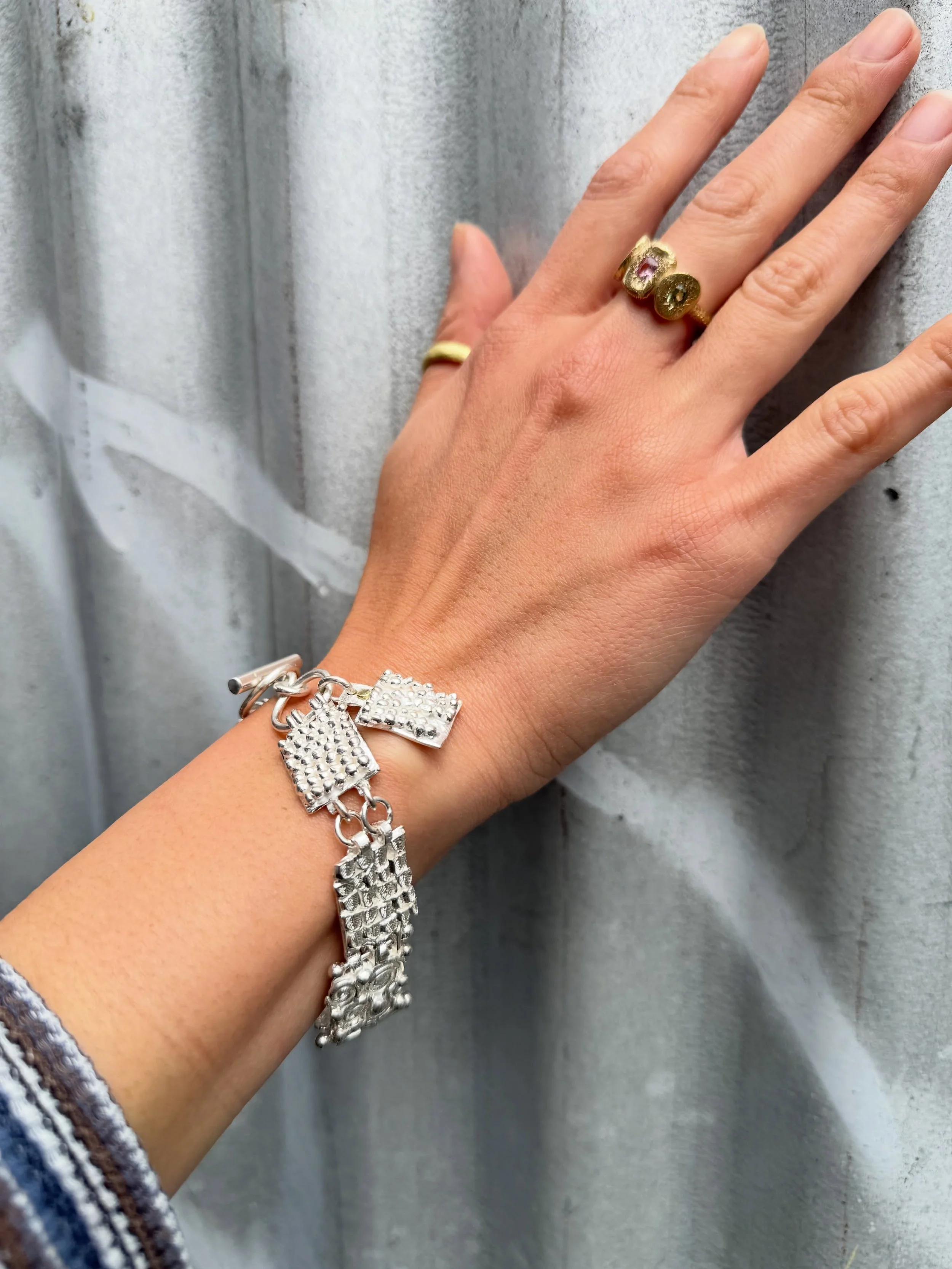 #178. Series of One.

This bracelet is a treasure trove of textures and patterns and sensory experiences. Something to play with when worn, something to anchor oneself when out in the world.

Inspired by the traditional charm bracelet, this new handm