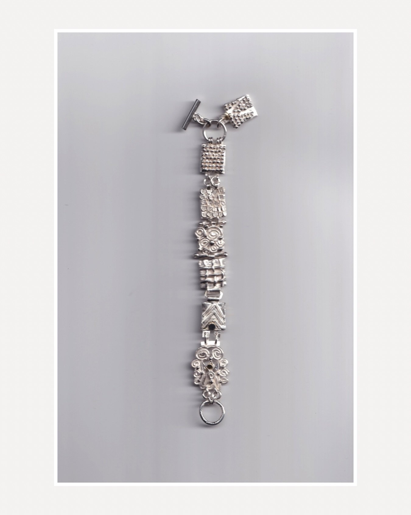 Inspired by the traditional charm bracelet, this new handmade piece reimagines the way charms are worn. Rather than hanging freely, they run across the wrist, creating a distinctive arrangement of individual forms.

#178. Series of One.

Handmade in 