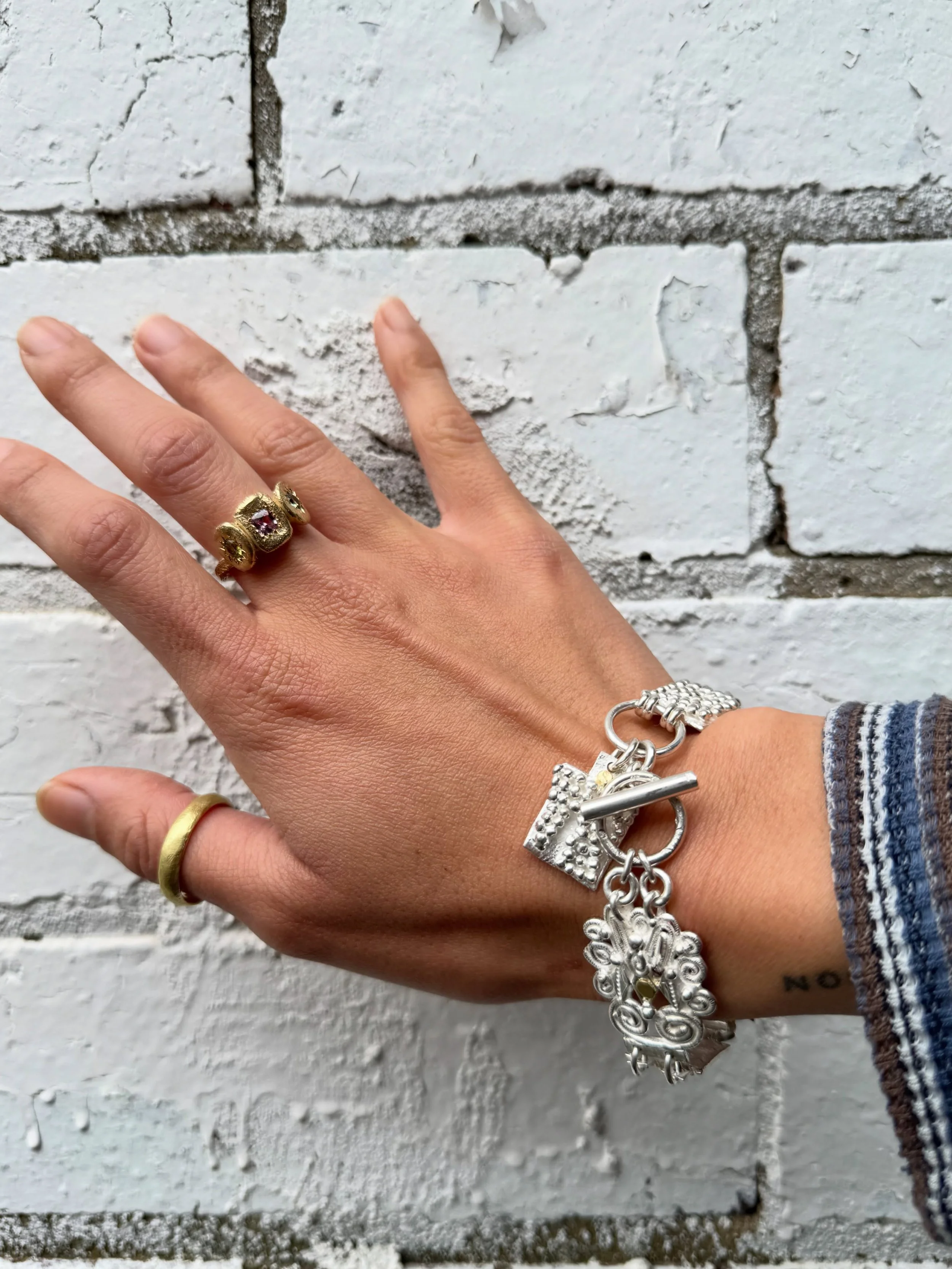 #178. Series of One.

This bracelet is a treasure trove of textures and patterns and sensory experiences. Something to play with when worn, something to anchor oneself when out in the world.

Inspired by the traditional charm bracelet, this new handm