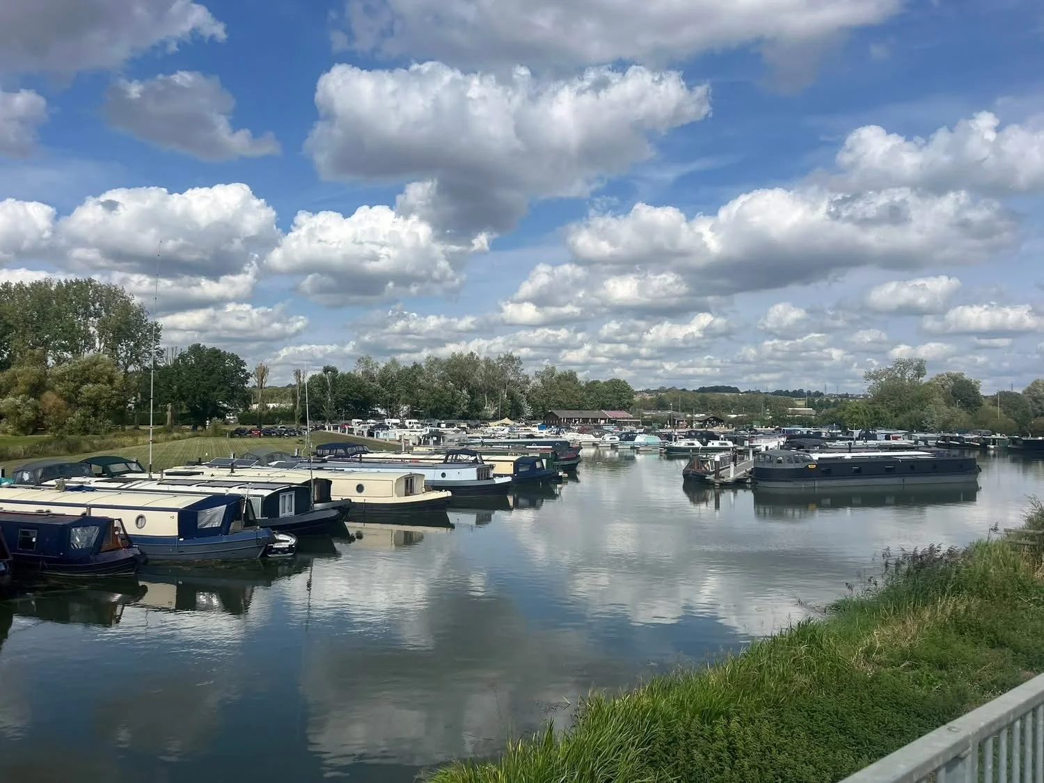 Narrowboats moored on marina blue skies puffy clouds and beautiful reflections
