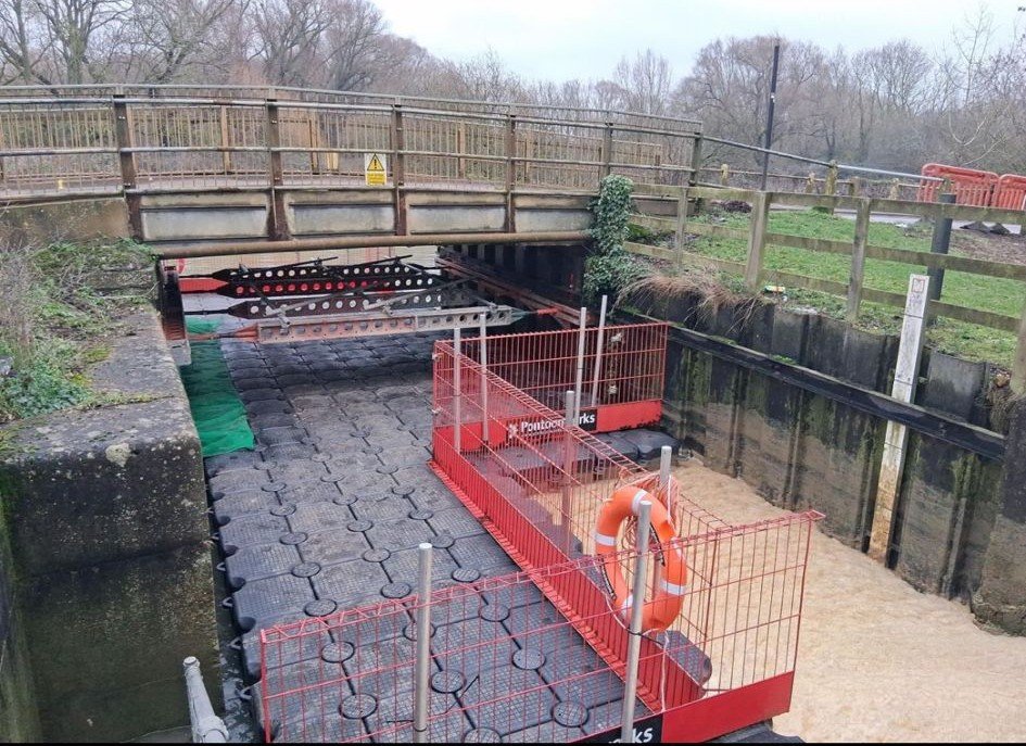 Bridge with black floating pontoon with red caging underneath
