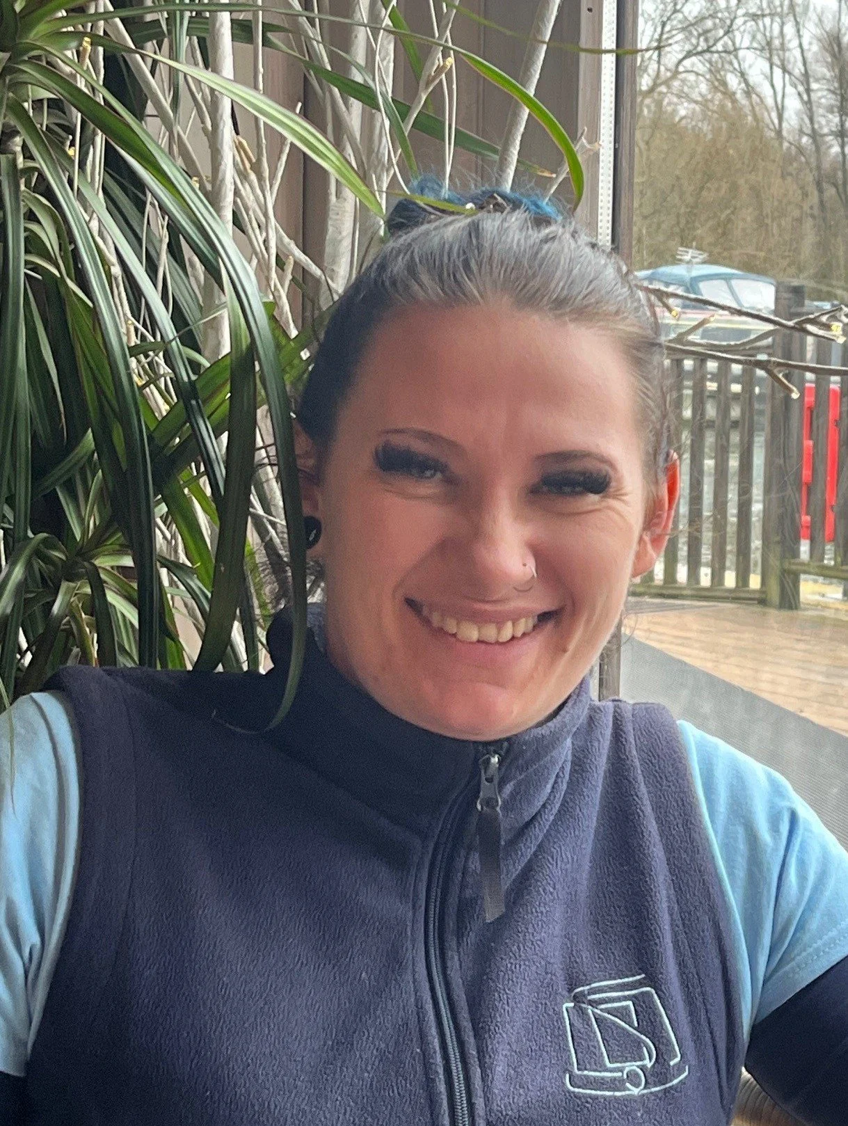Smiling young woman surrounded by foliage overlooking the marina