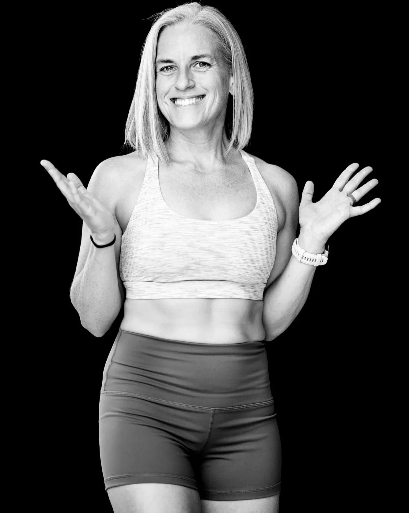 A woman smiling with arms open portraying a welcoming gesture.