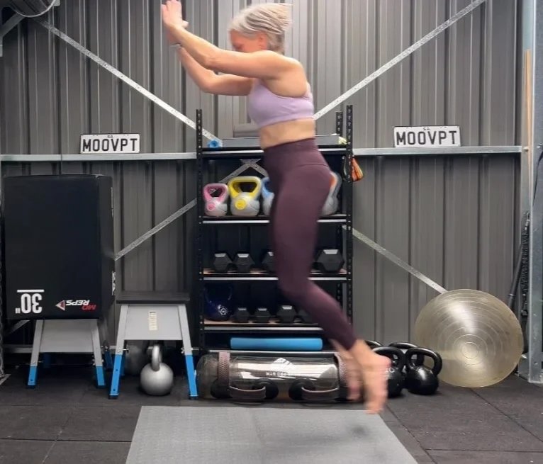 a woman doing a broad jump which is power training exercises across a mat in a shed home gym