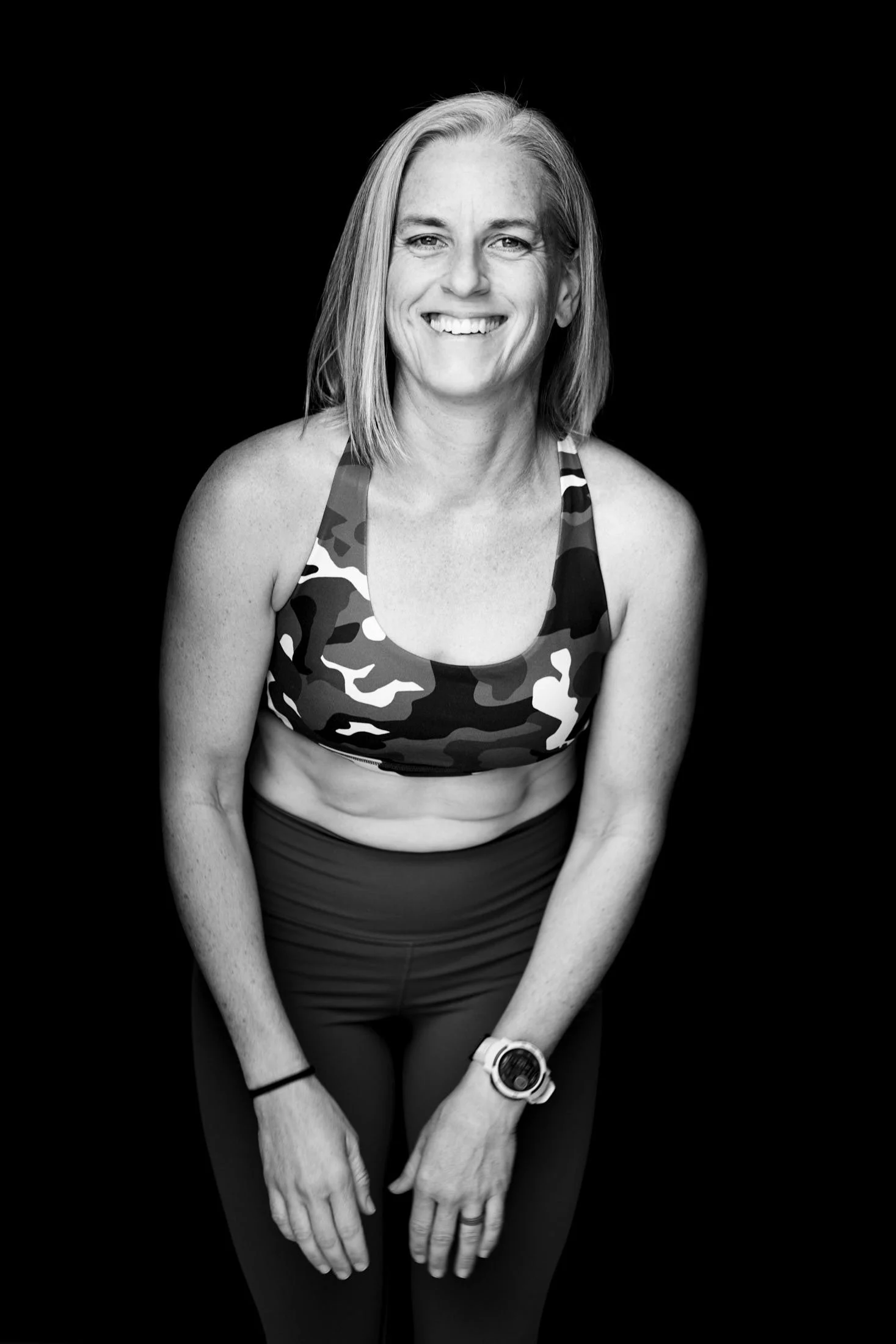 A woman laughing in workout clothes with her hands resting on her legs ready to do strength training as a woman over 40