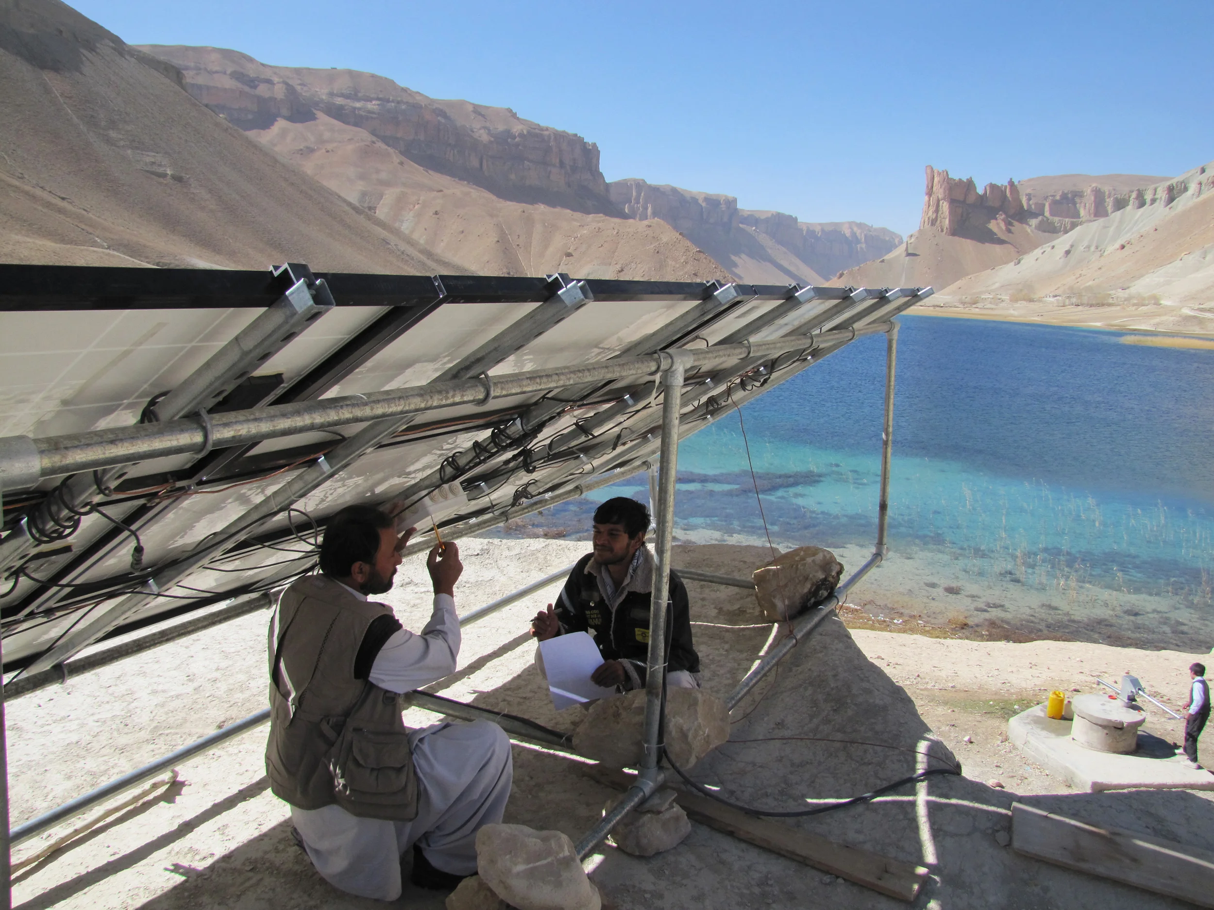 USAID is supporting the electrification of rural schools in Afghanistan, through projects like the Afghanistan Clean Energy Program (ACEP). ACEP created a 2 kW solar-powered system to provide power to the Shaheed Mahmoodi High School in Band-e Amir National Park in Bamiyan Province, benefitting its 621 male and female students. Here Afghan technicians are finishing installation and testing of the solar array. Photo credit: Robert Foster, Winrock International.