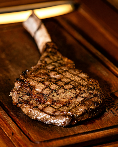 Grilled ribeye steak with crosshatch grill marks on a wooden board
