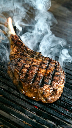 Bone-in rib roast searing on a grill with visible smoke and grill marks
