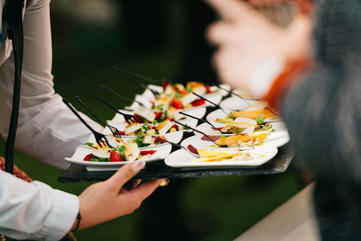 Server holding a tray of small appetizers at an event