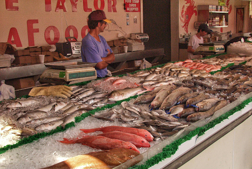 Seafood counter with fresh fish fillets displayed on ice and staff behind the counter